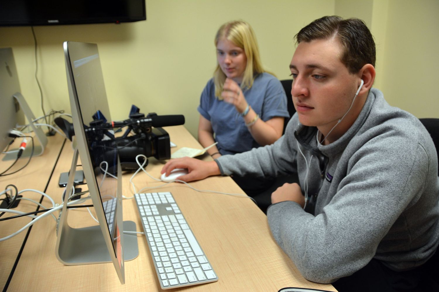 Students working at computer stations in a classroom lab setting.