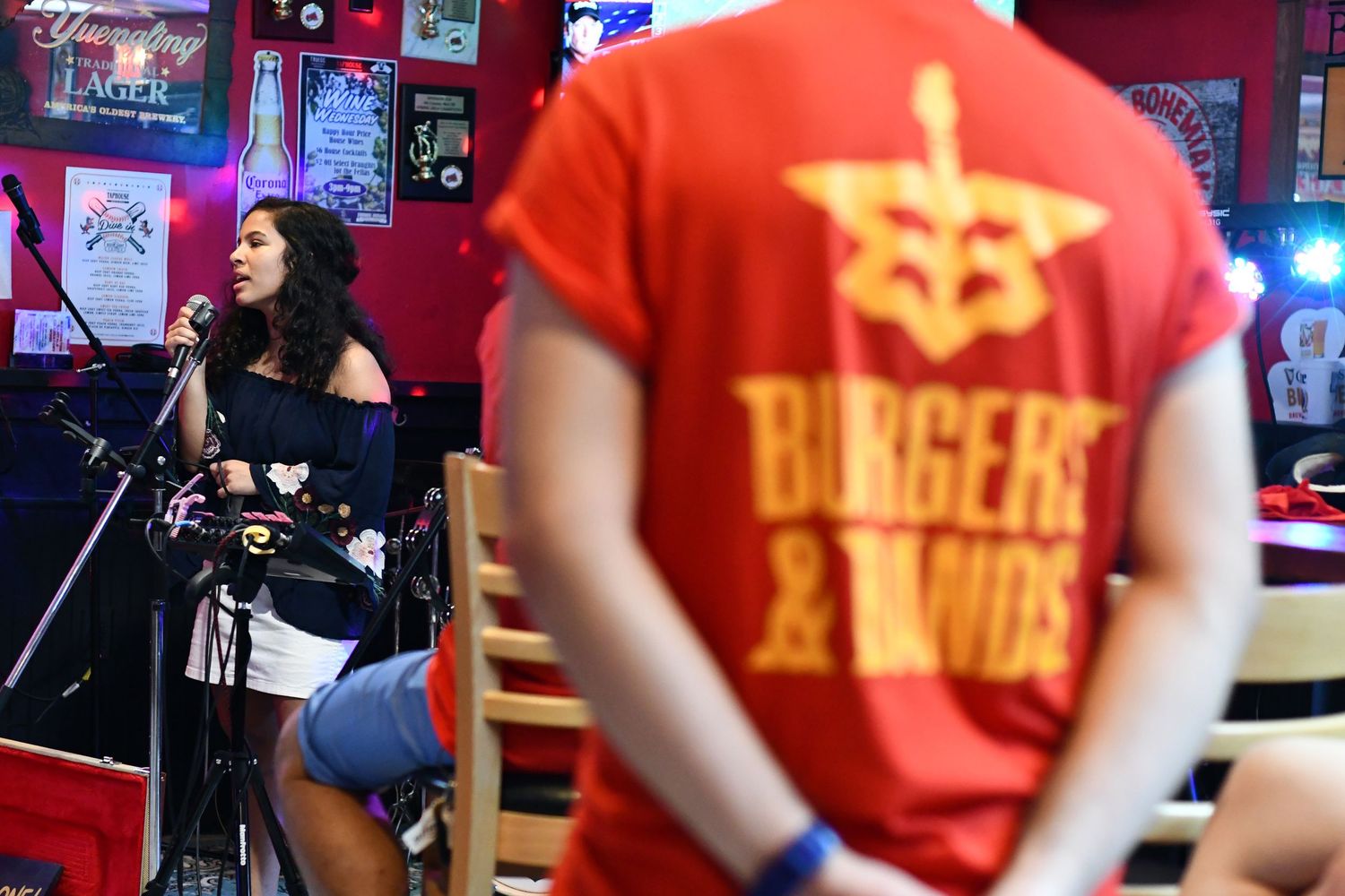 Musicians performing on stage with red t-shirts and instruments.