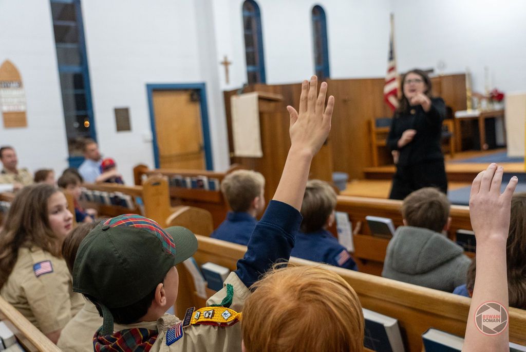 Attendees sit in wooden pews during a community meeting or presentation.