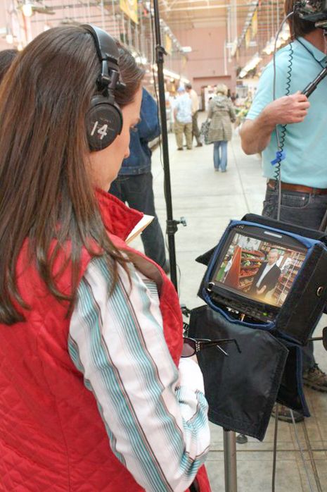 Camera operator using professional video equipment with external monitor outdoors.