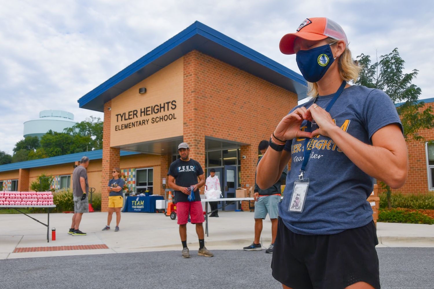 Staff member wearing a mask gestures while speaking outside Tyler Heights Elementary School.