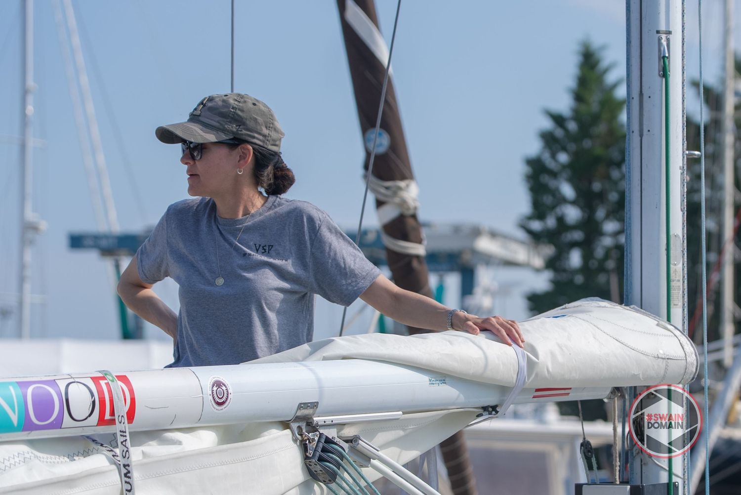 Sailboat crew members adjust and handle white sails during a competitive sailing race on blue waters.
