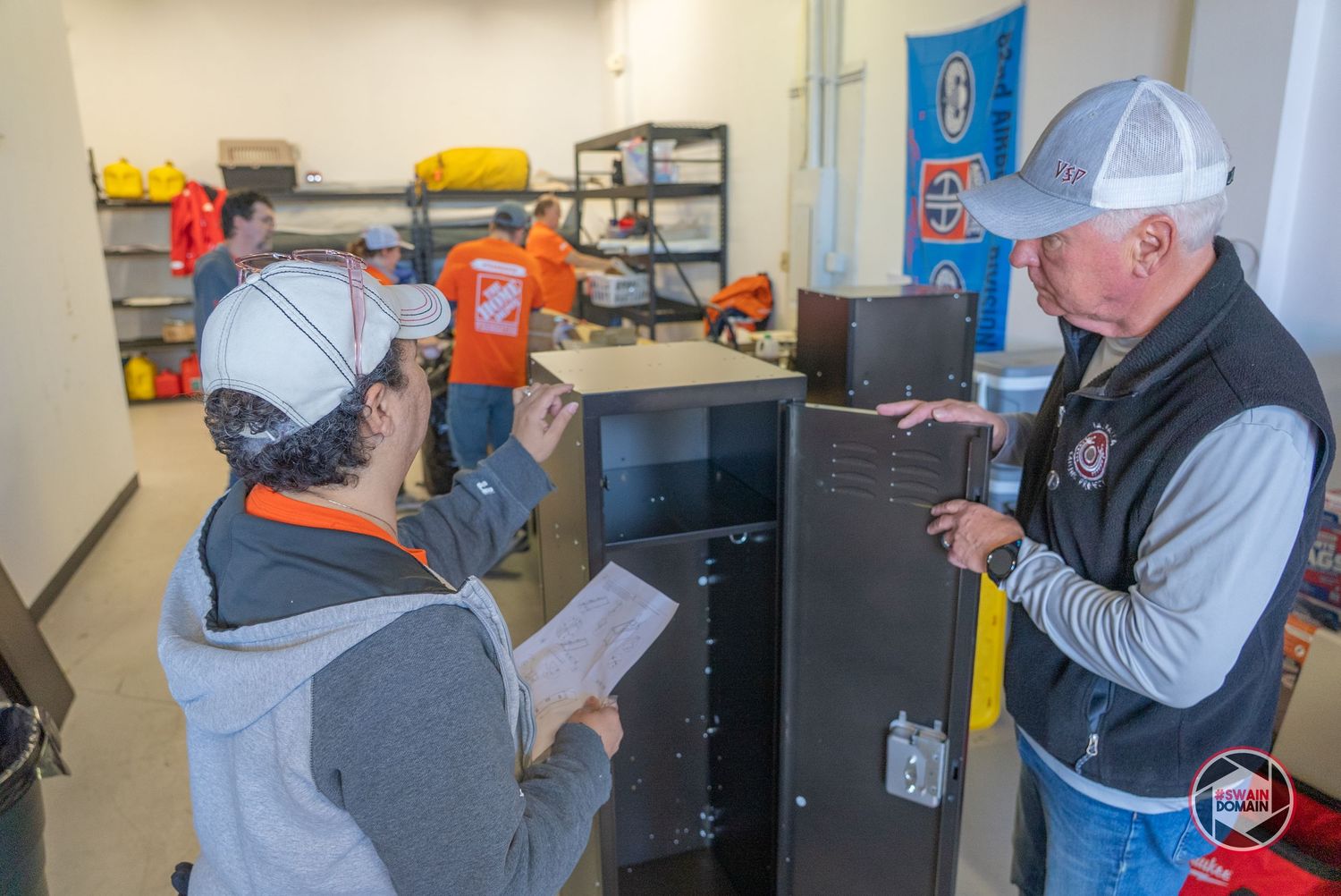 Maintenance worker in safety gear performs electrical testing on industrial equipment with a handheld device.