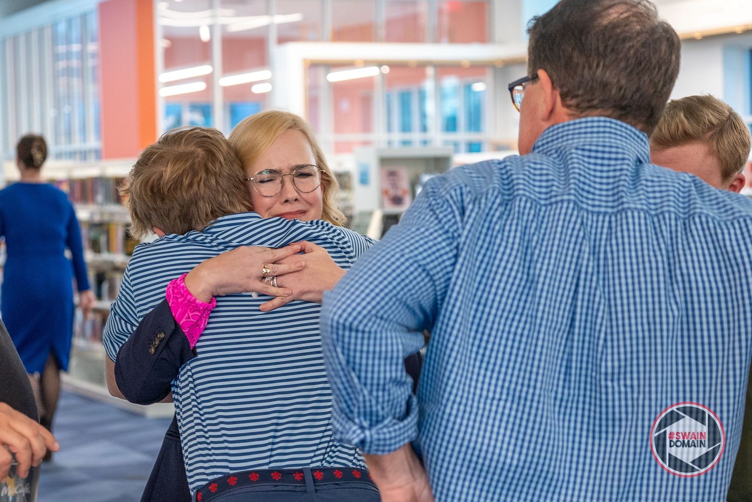 Row of people in blue shirts seen from behind at a gathering.