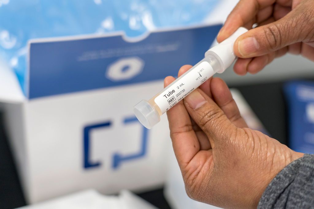 Close-up of hands holding a white testing device or instrument.