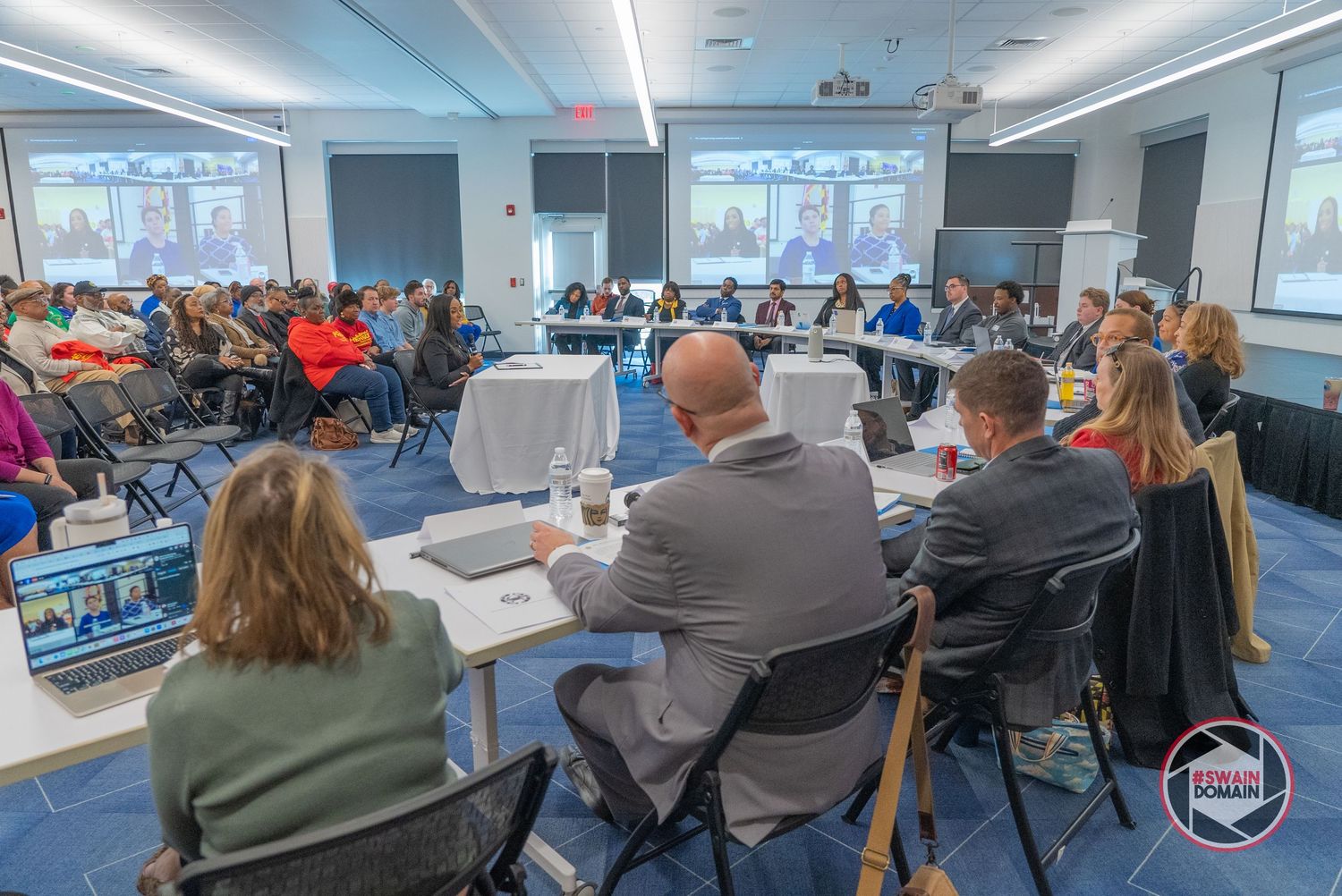 Large conference room filled with attendees viewing presentations on multiple screens.
