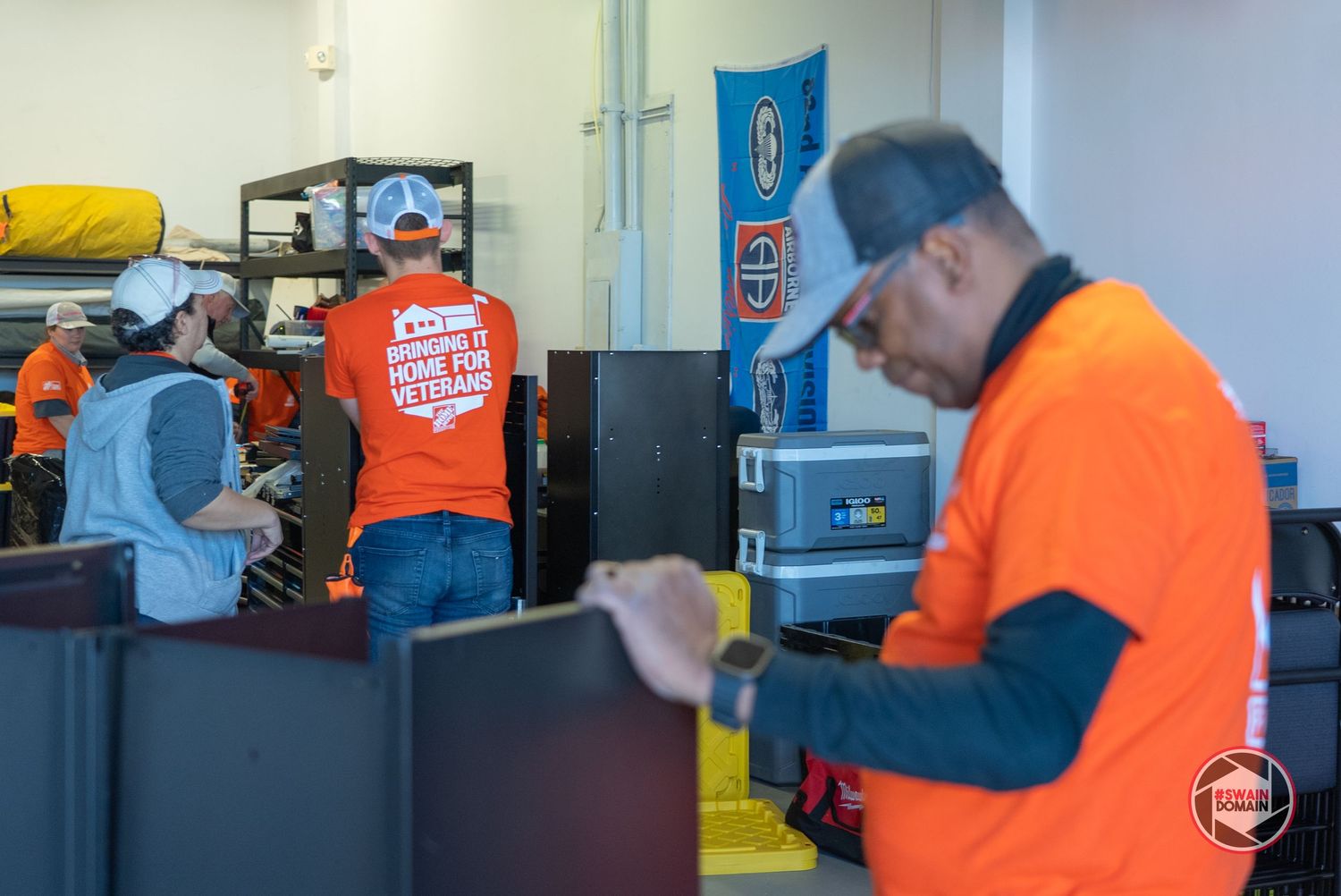 Workers in high visibility orange safety gear performing maintenance tasks in an industrial facility.