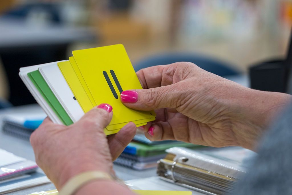 Hands sorting through paper documents or files on a desk surface.