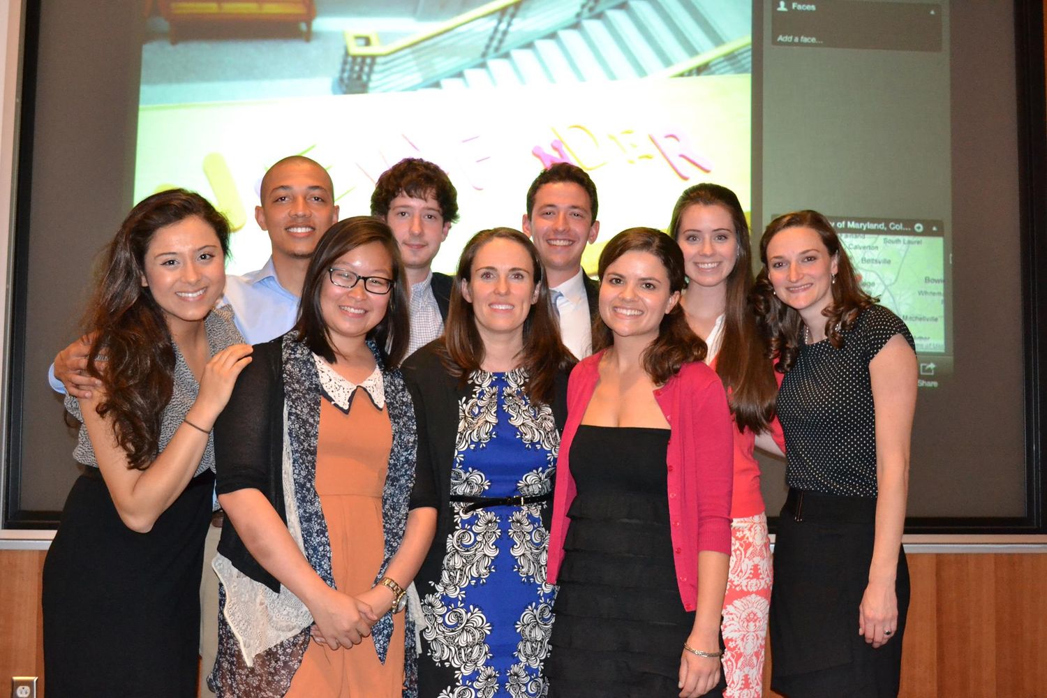 Group photo of students posing together in front of a presentation screen.