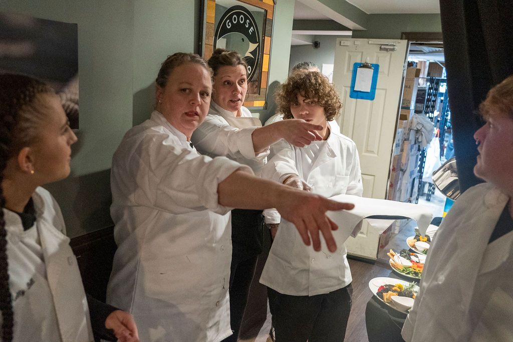 Kitchen staff in white uniforms preparing food in a commercial kitchen.
