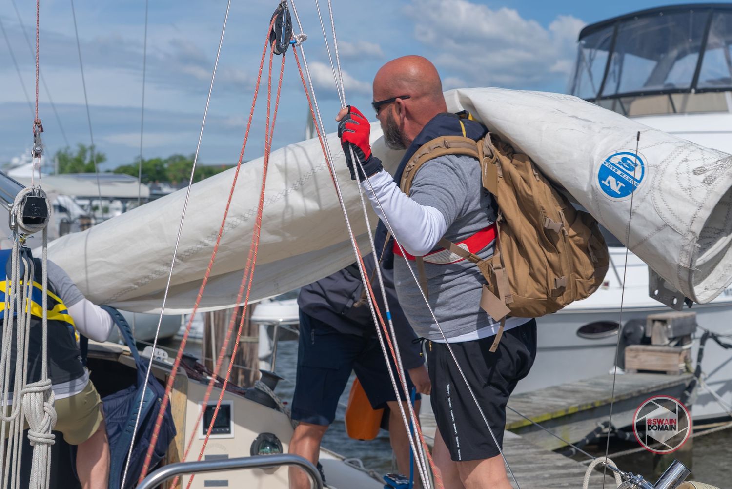 Sailors work together on a sailboat deck during a race or training session at sea.