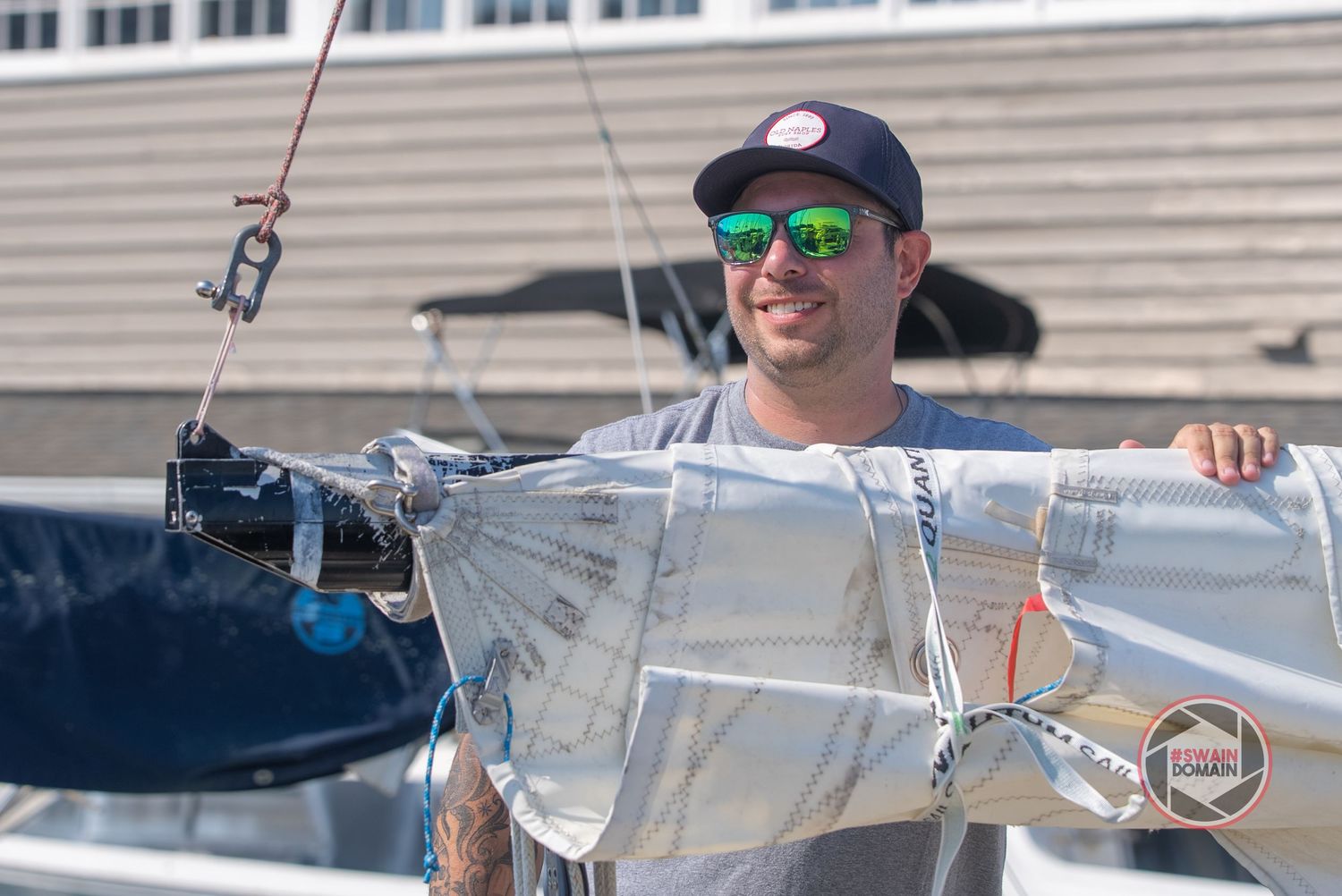 Sailing crew members working together to adjust and maintain sails on a racing yacht during competition.