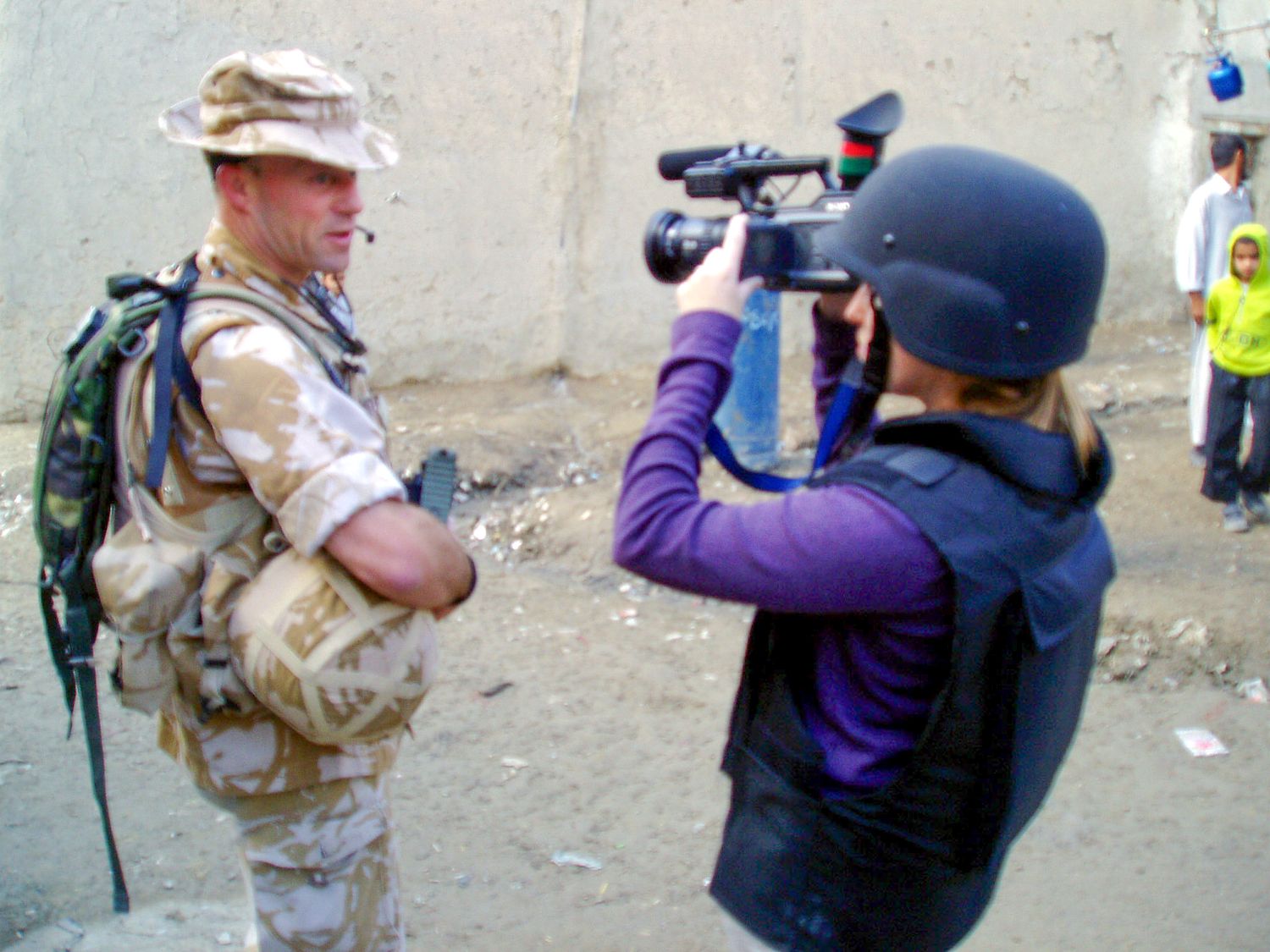 Military personnel and camera operators filming in desert terrain.