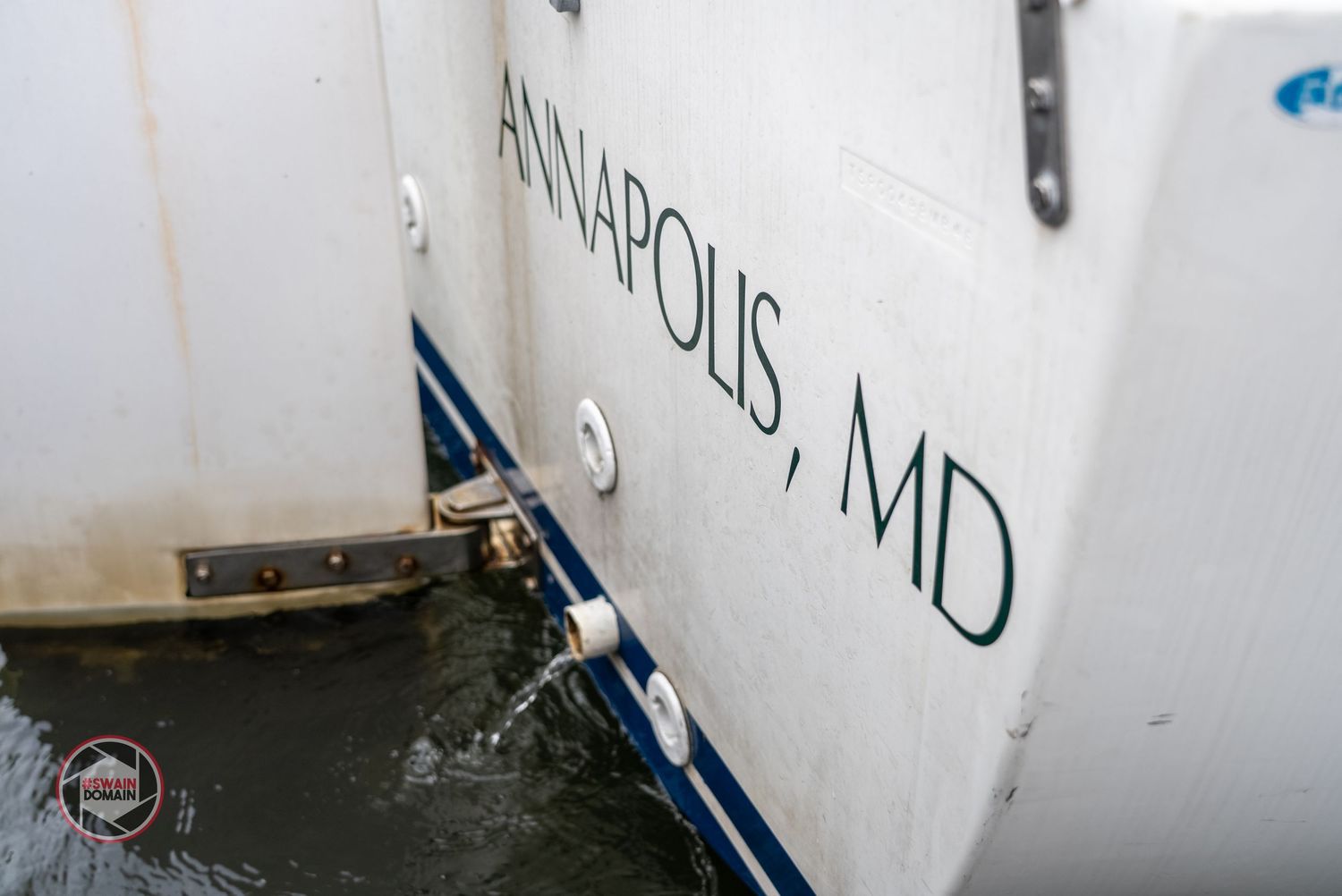 A close-up view of a white boat hull showing registration numbers and waterline markings.