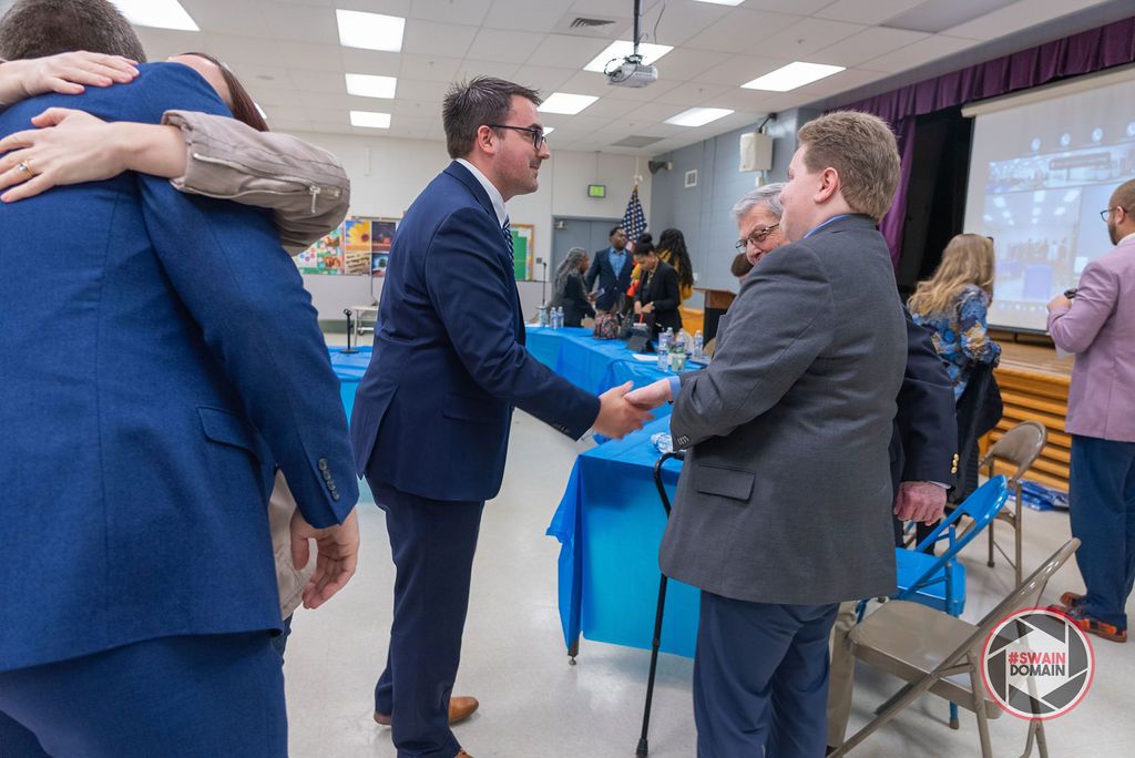 Professional networking event shows people in suits having conversations in a meeting space.