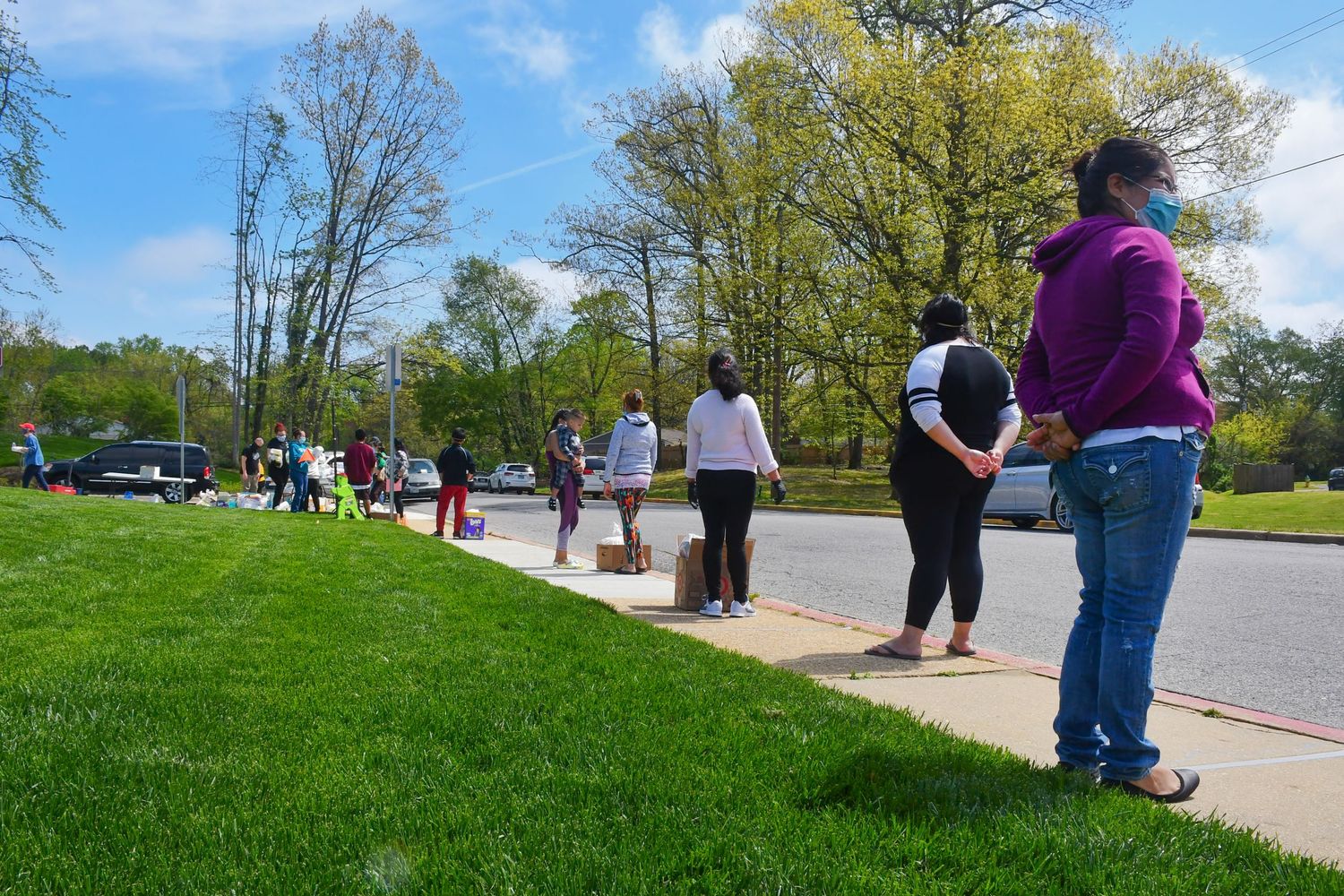 People enjoying a sunny spring day on grassy lawn near walking path.