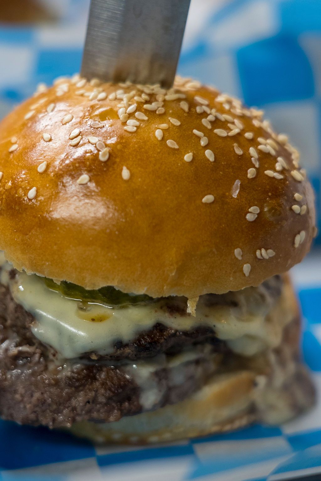 Close-up of a juicy cheeseburger with sesame seed bun and melted cheese.