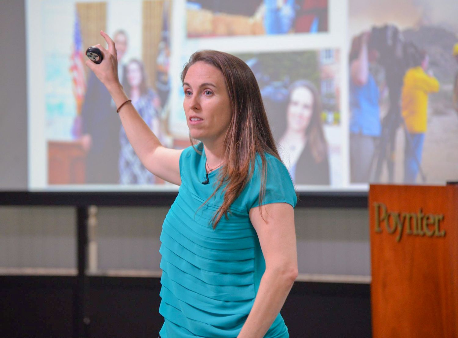 Presenter gesturing on stage with projected presentation screen in background.