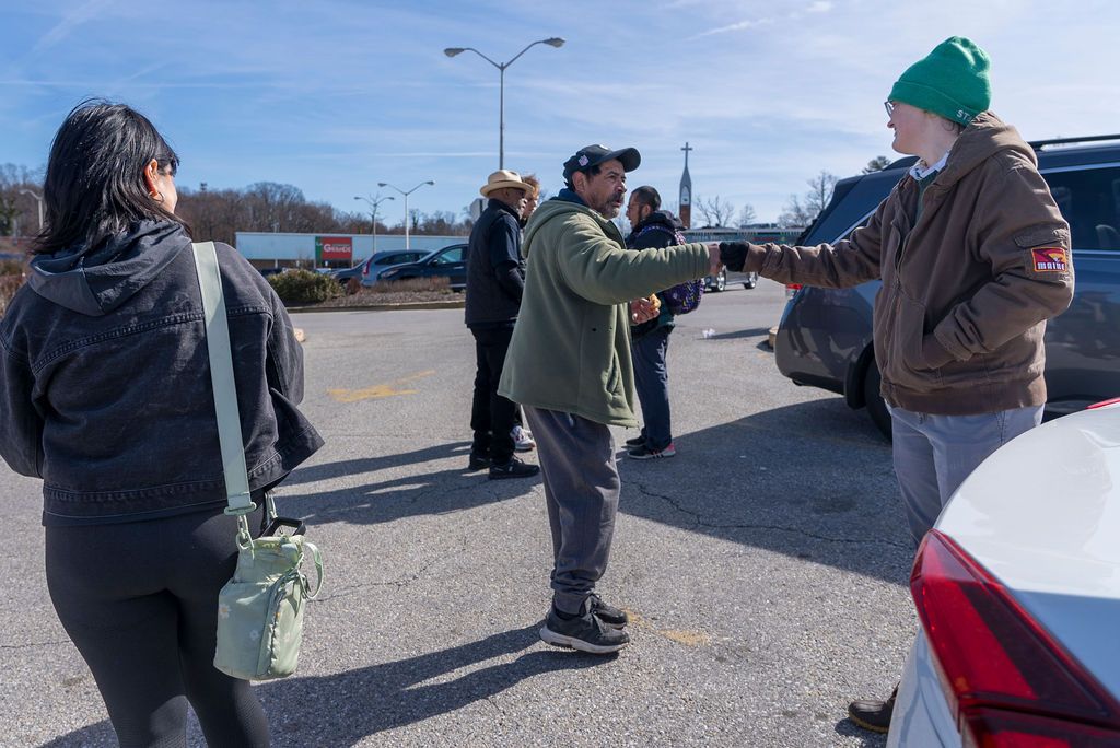 People gathered in a parking lot on a sunny day.