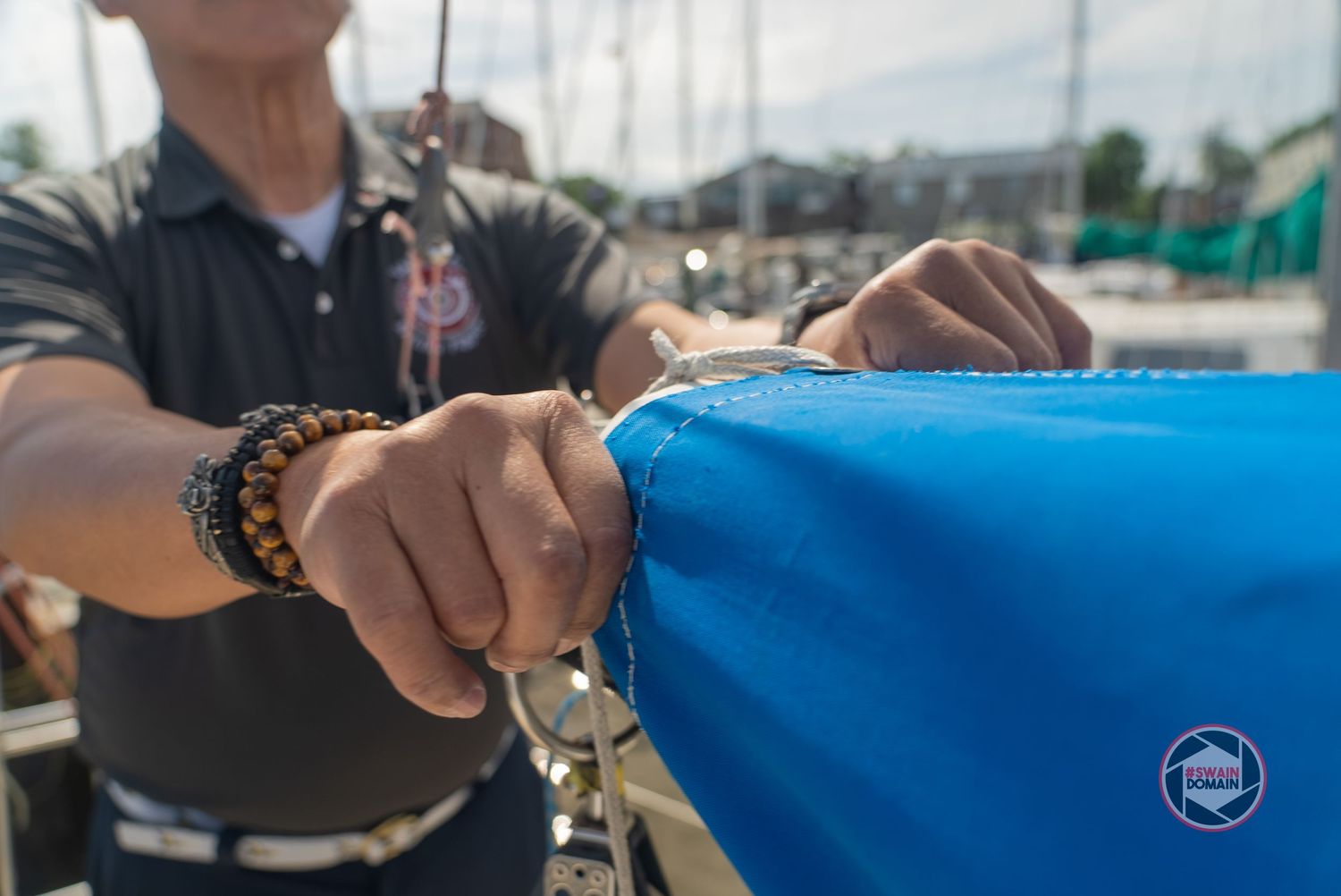 A series of hands holding fishing rods and reels against a blue sky and water background.
