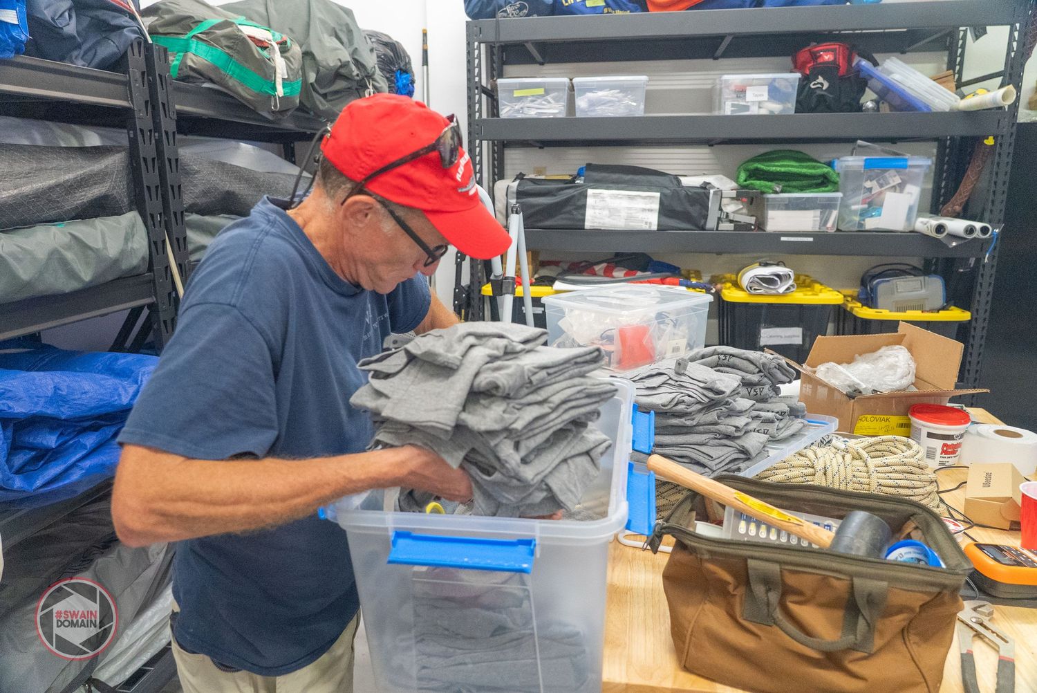Person working on electronics repair and assembly at a workbench with tools and components spread out.
