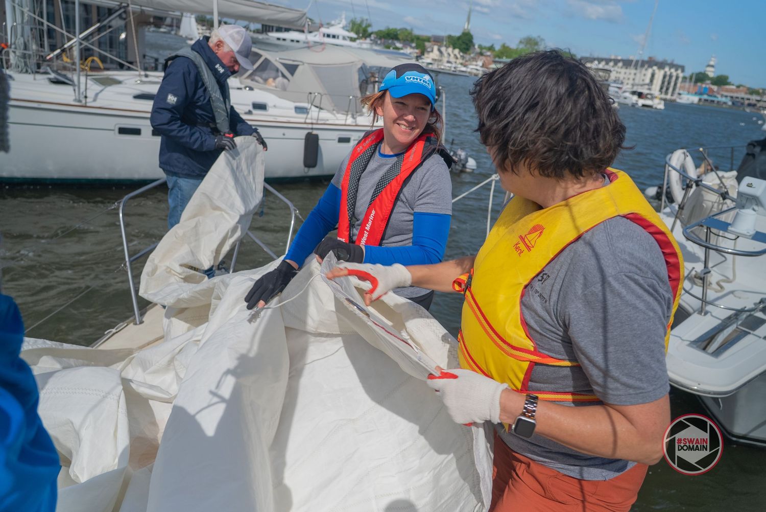 Scientists in safety vests collect and process water samples on a research vessel at sea.
