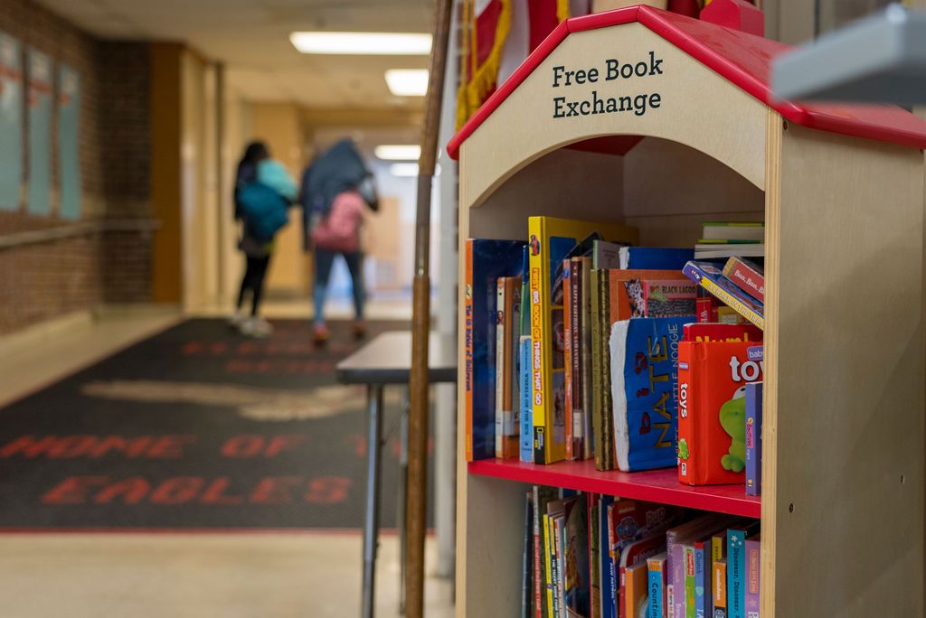 Library shelves with books and a Free Book Exchange sign visible.