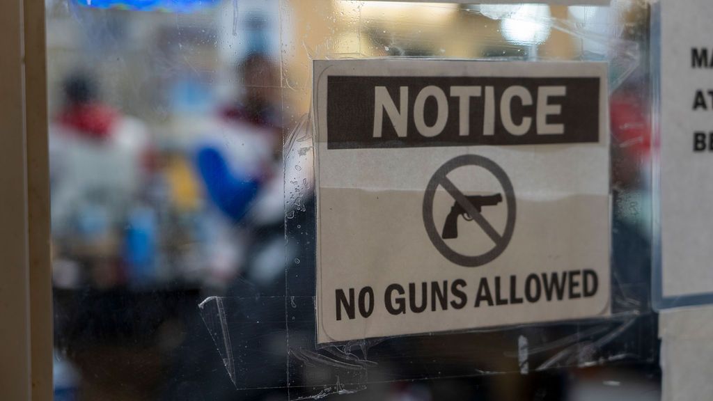 A row of 'No Guns Allowed' signs mounted on a wall.