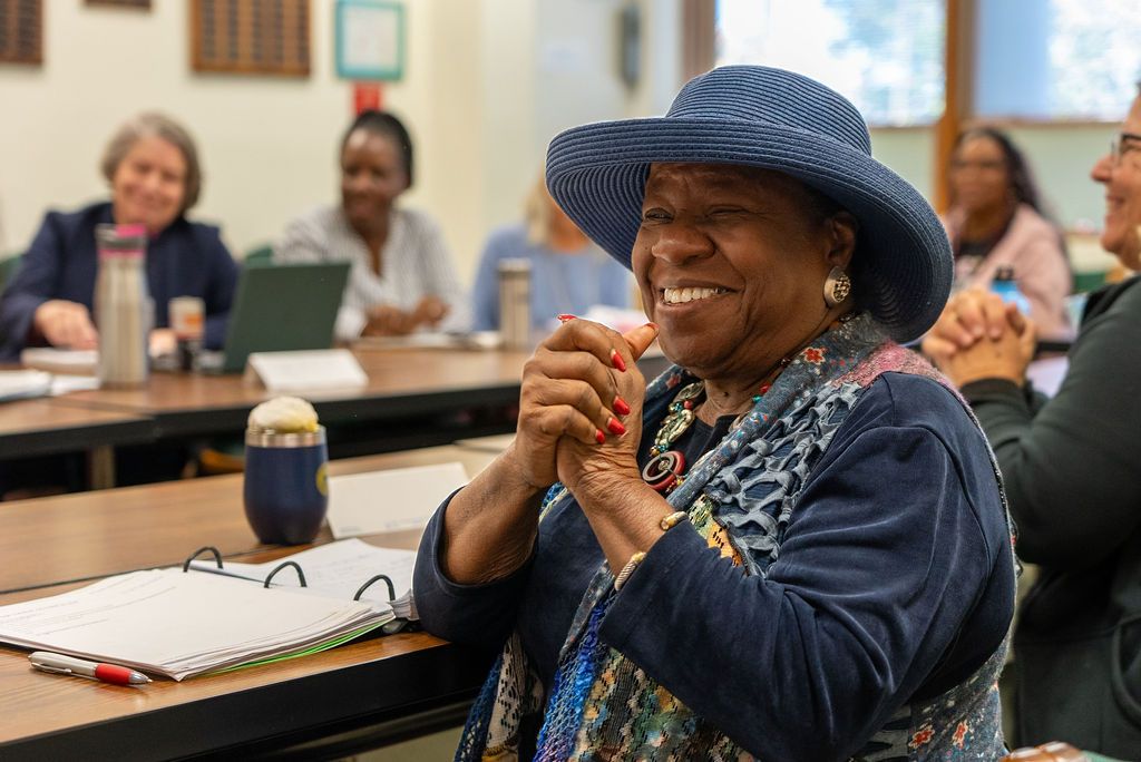 A person in a blue hat participates in a classroom discussion.