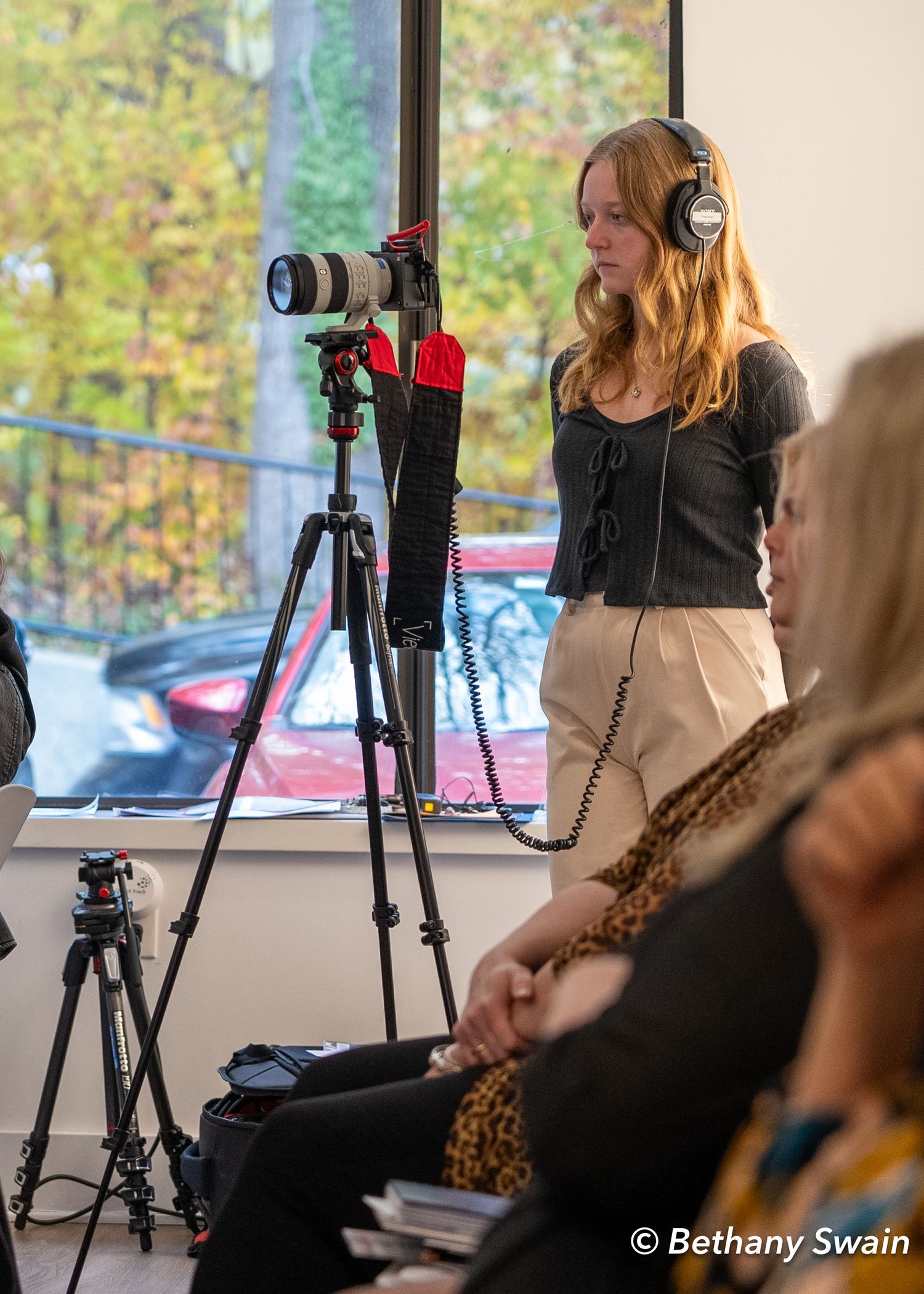 Photography setup with multiple cameras and tripods in front of window with natural lighting.