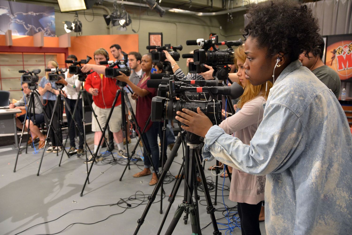 Students practice photography with professional cameras in a classroom setting.