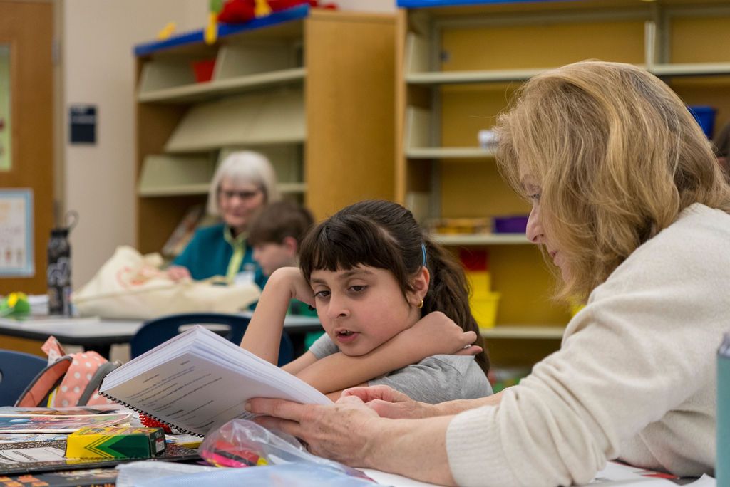 Students working together at tables in a classroom or library setting.