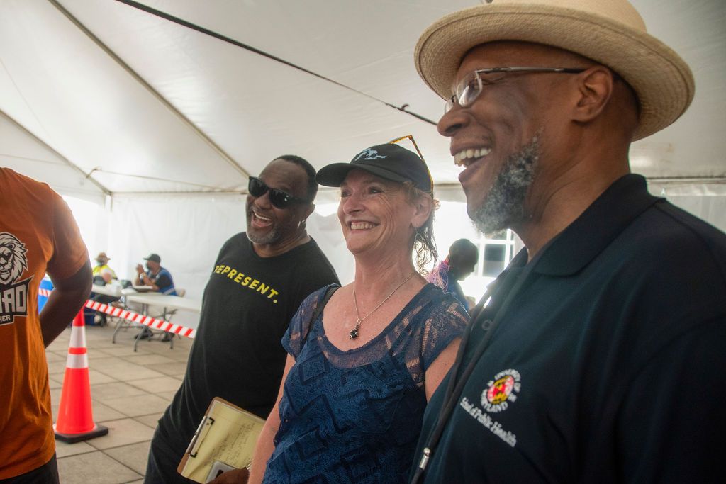 A group of people gathered under a white tent at an outdoor event.