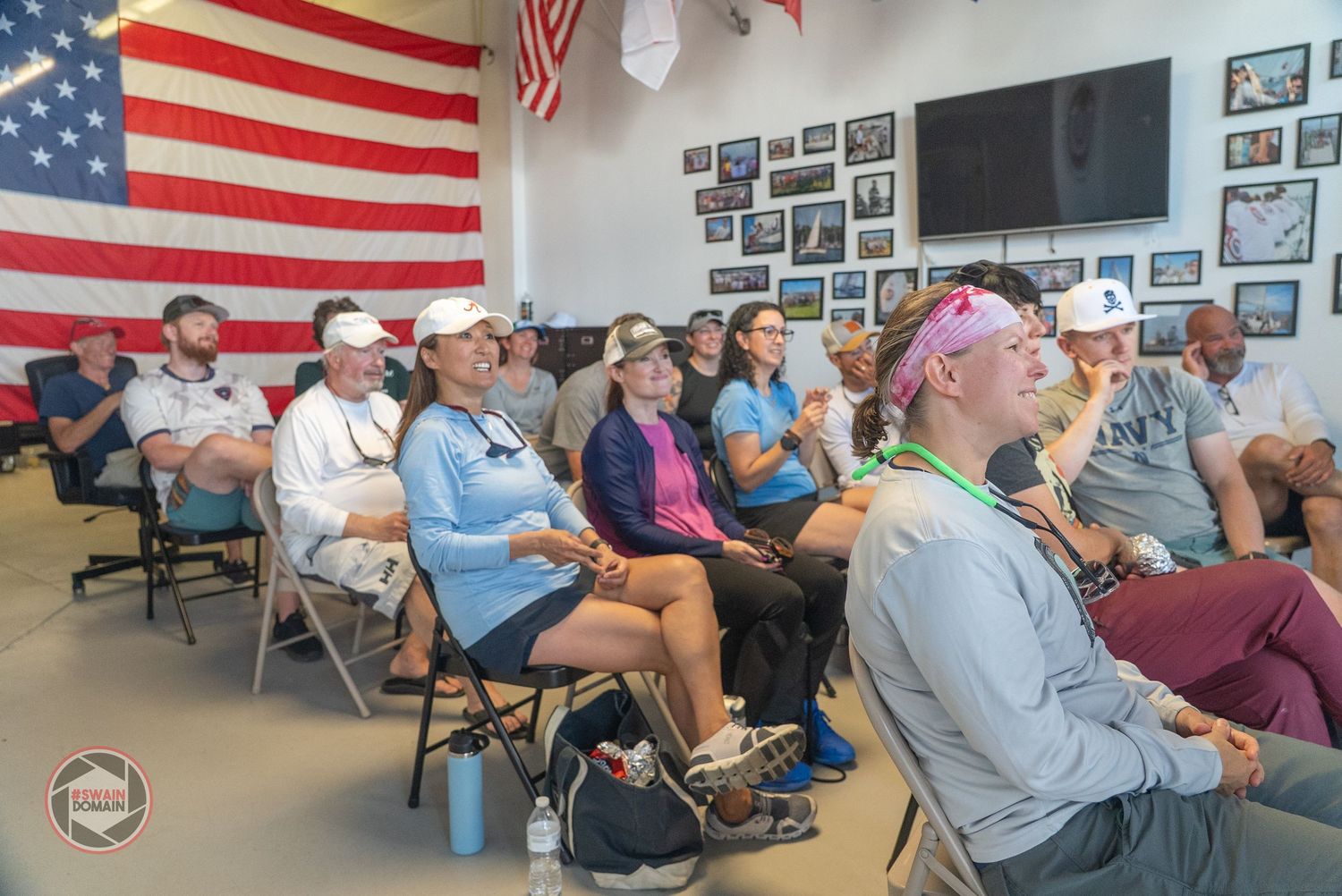Veterans gather in a community center with American flags displayed on the wall during a social event.