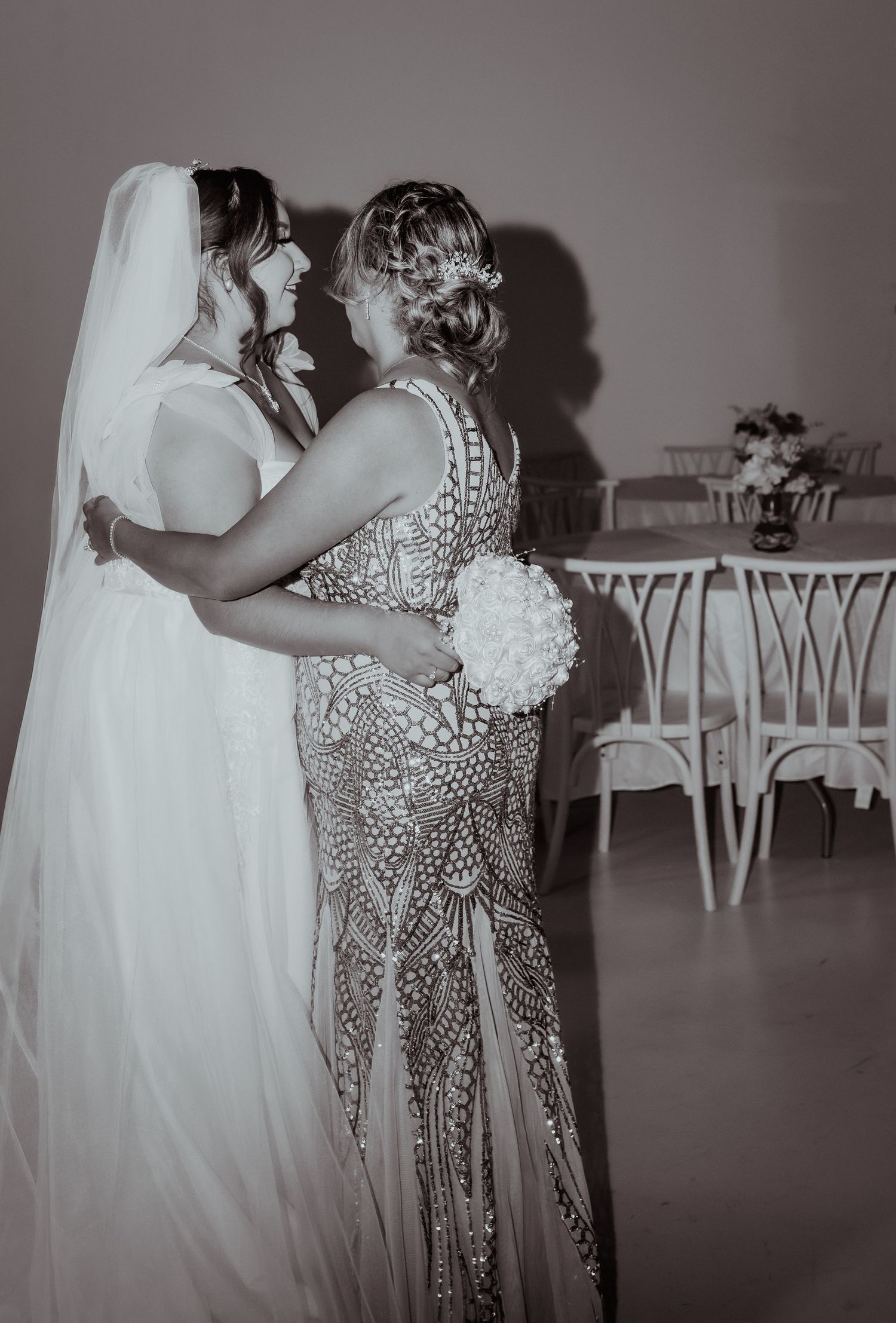 Two people in formal attire share an intimate dance at an event in black and white photography.