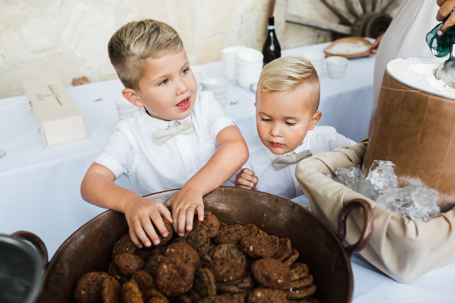 Young children in formal attire playing at a wedding reception table.