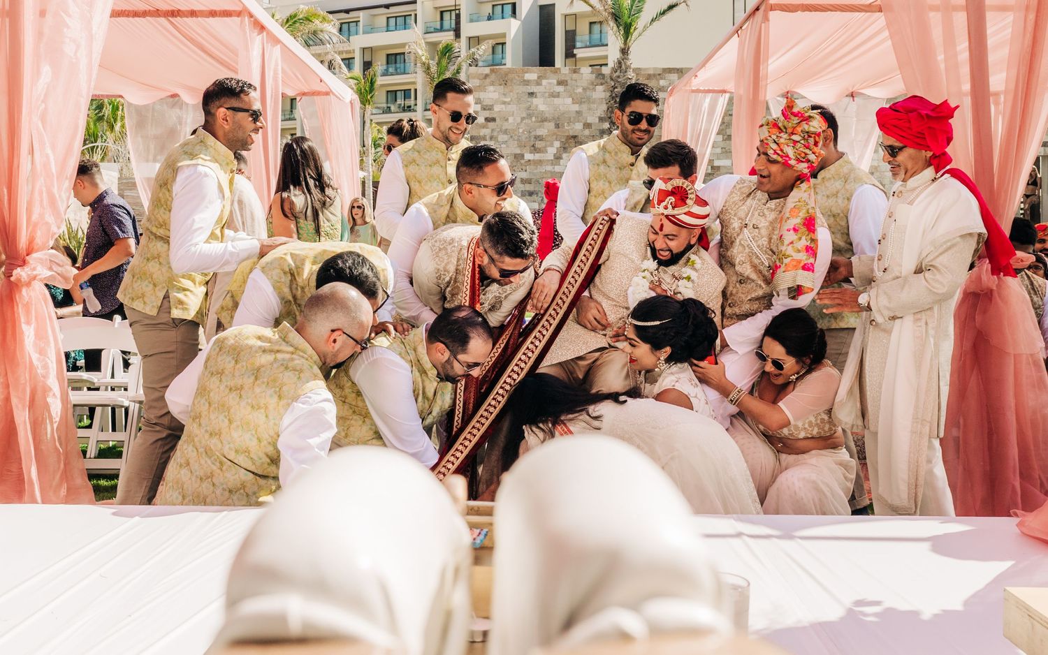 Wedding celebration with pink and coral decor under an outdoor tent.
