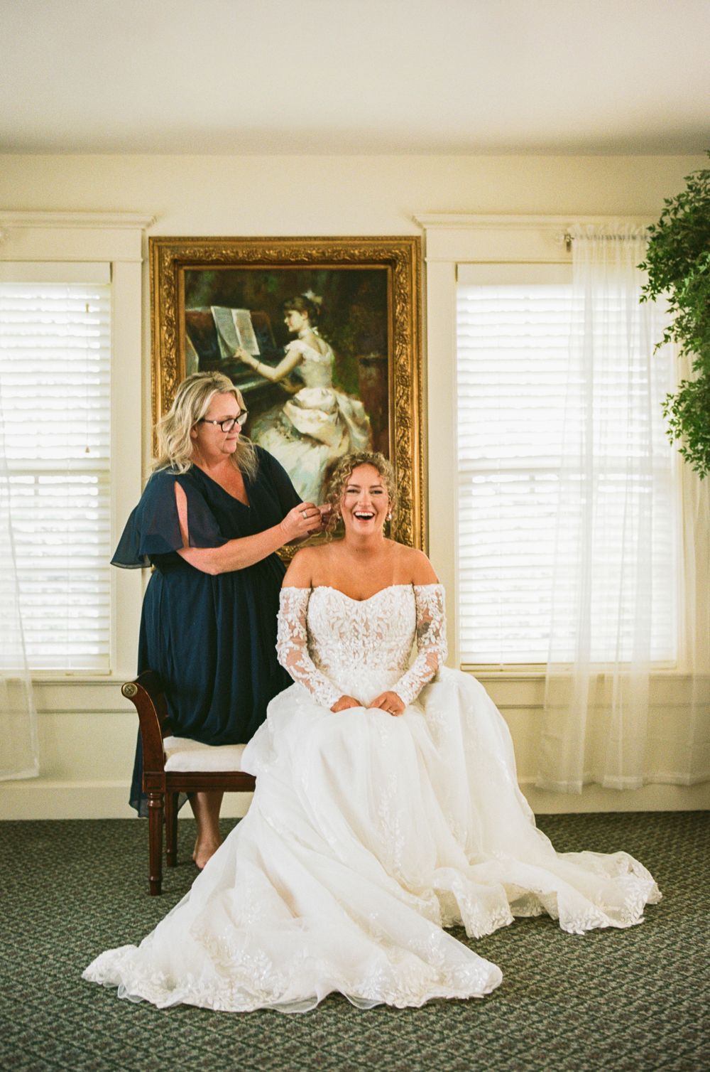 Wedding dress preparation in an elegant room with white decor and framed artwork.