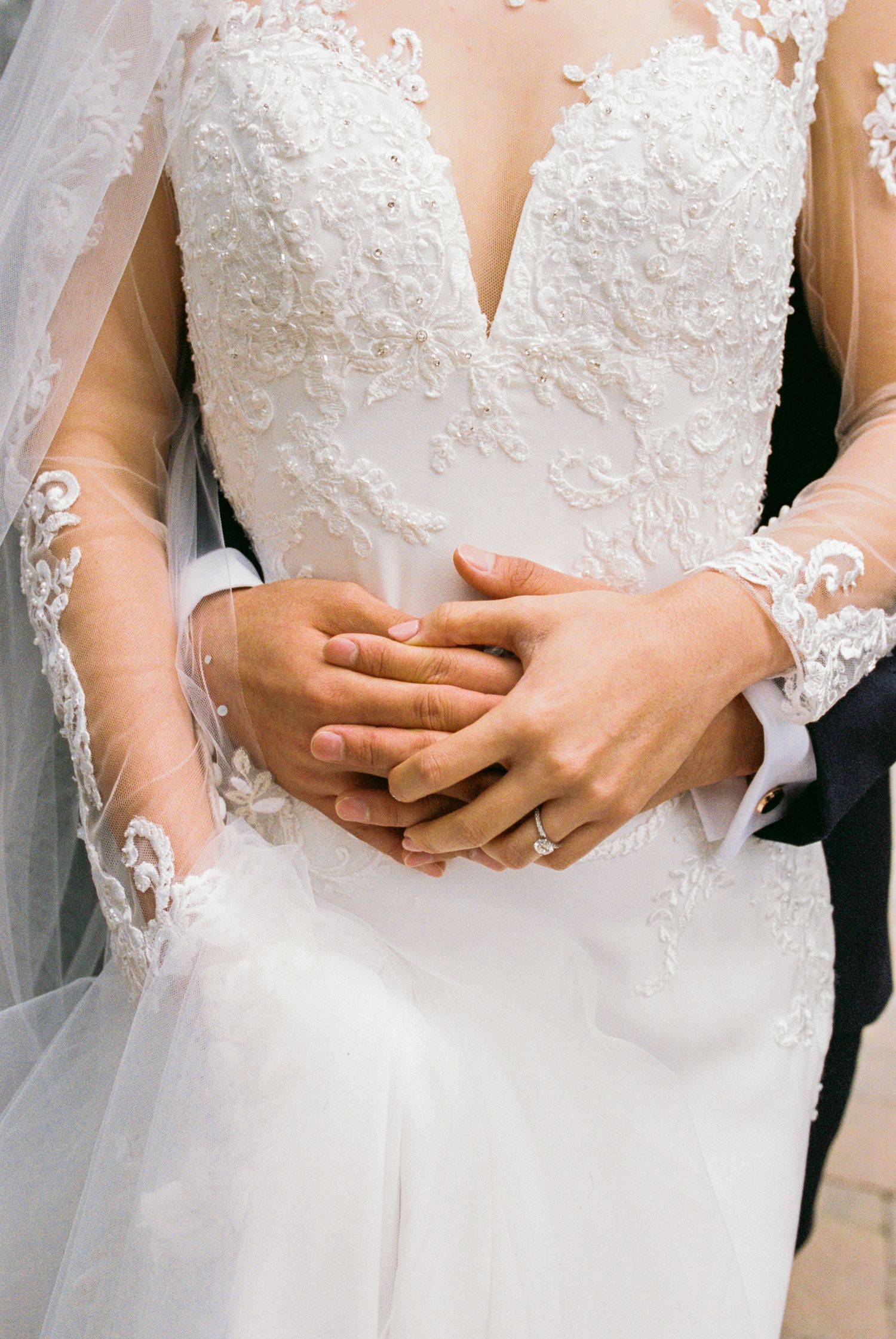 Close-up details of bride's intricate lace wedding dress bodice with delicate beading.