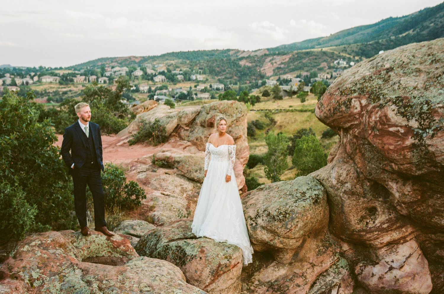 Couple poses on rocky mountain outcropping during wedding photoshoot.