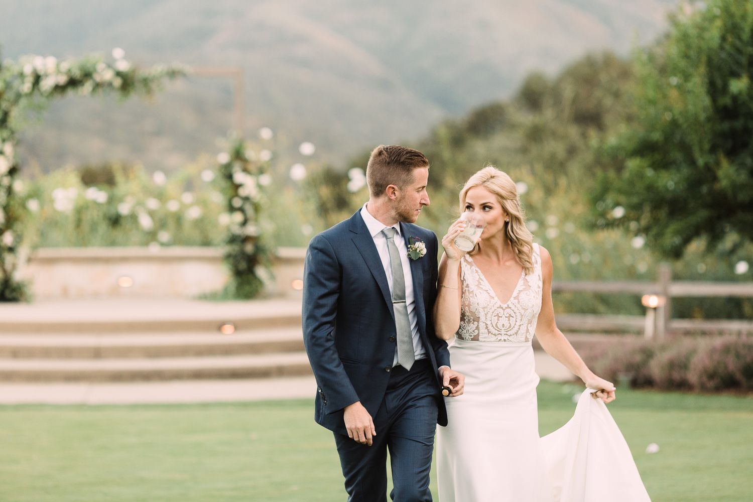 A wedding couple shares a joyful moment together outdoors against a mountainous backdrop.