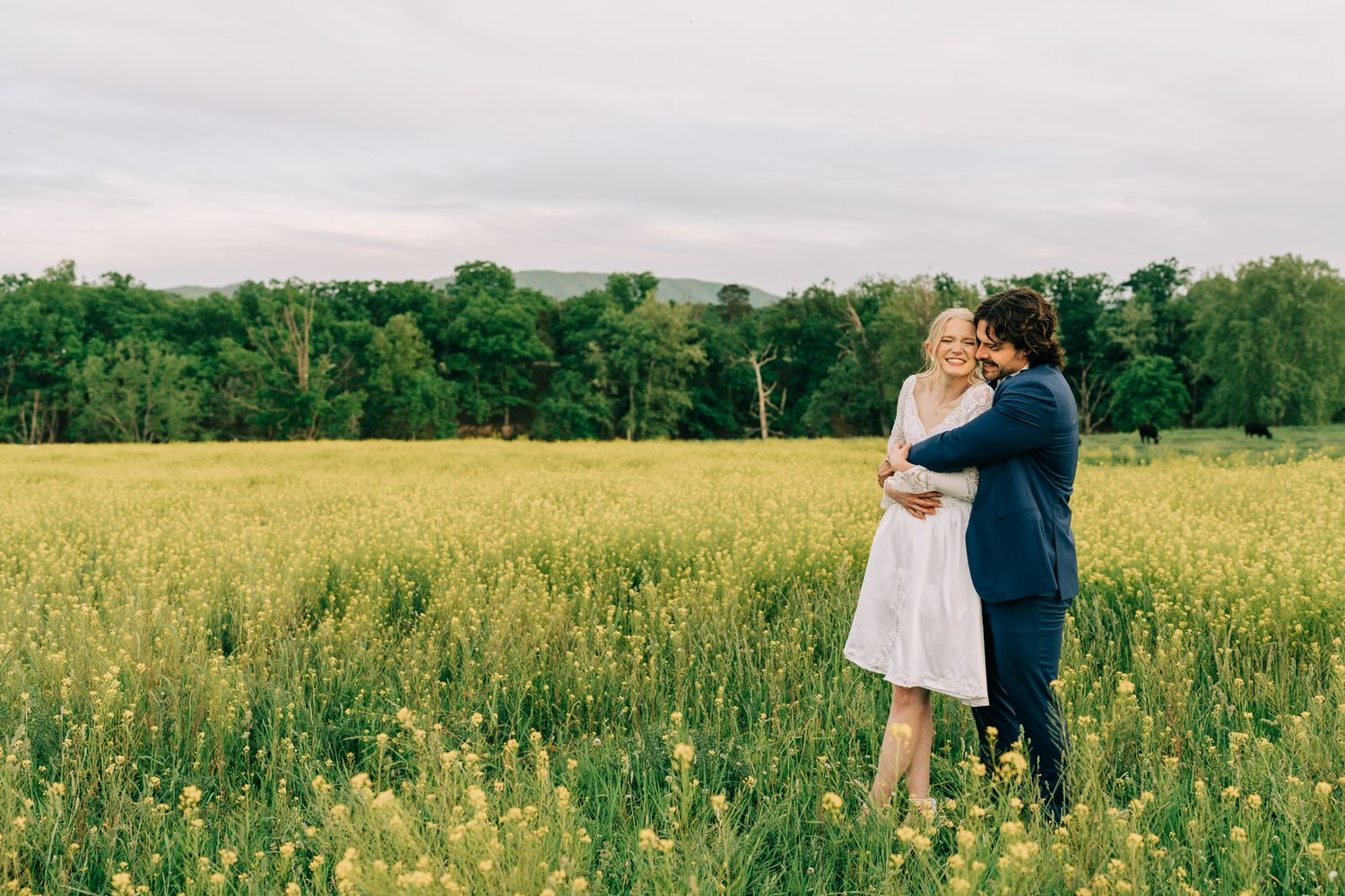 Romantic couple embraces in a sunlit meadow with wildflowers.