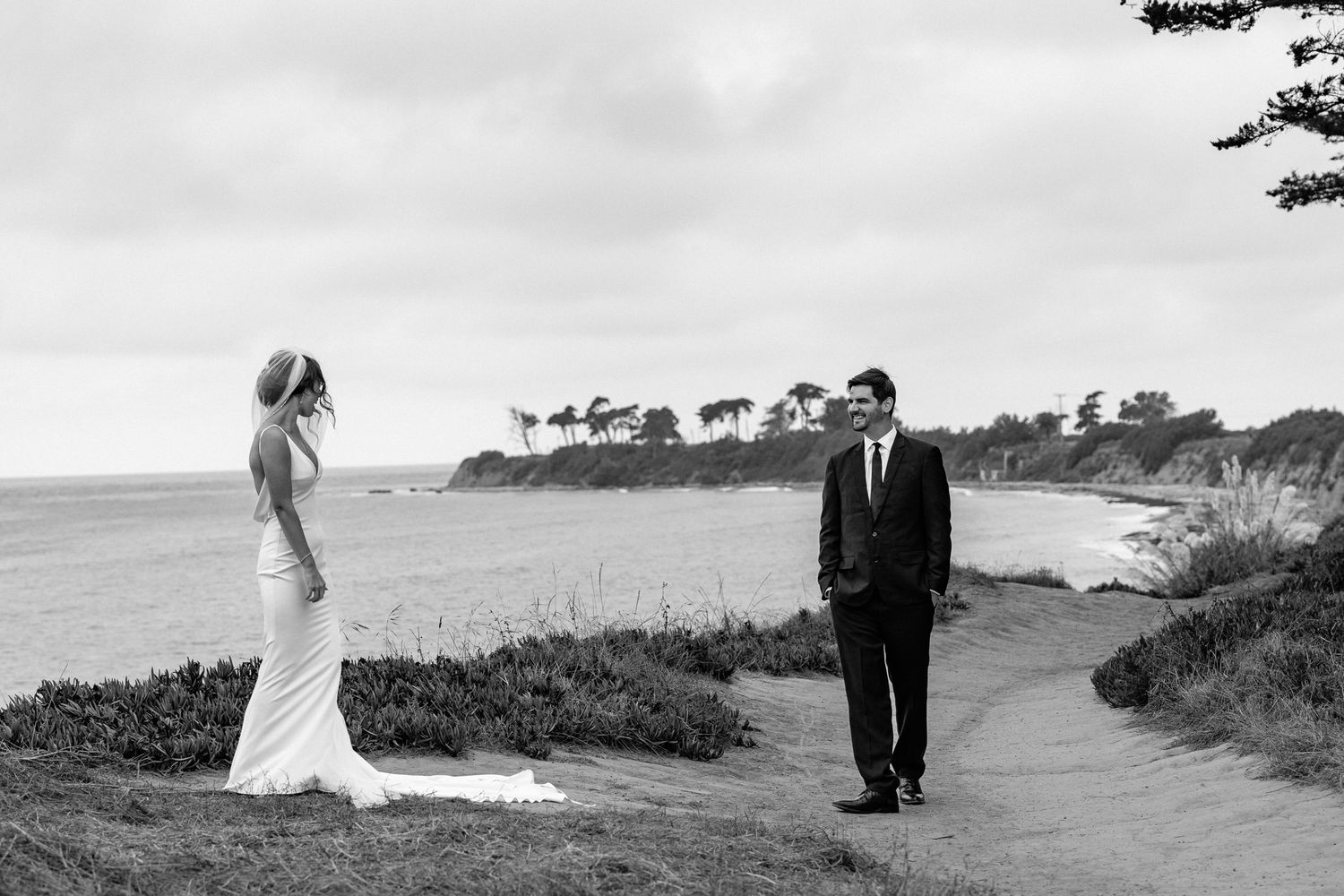 Wedding couple walking along a scenic coastal path overlooking the ocean.