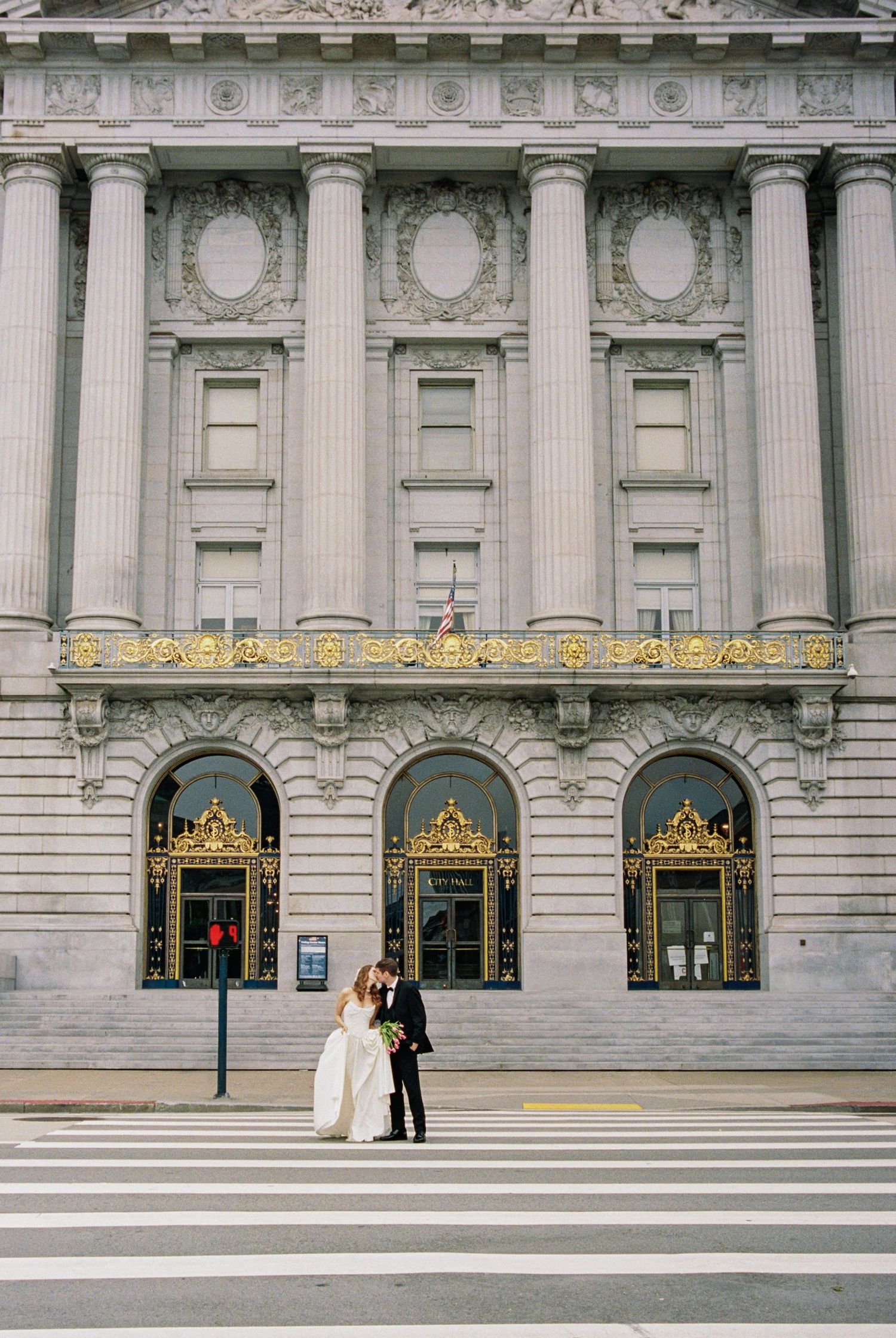 Couple shares a kiss on a crosswalk in front of San Francisco City Hall on their wedding day.