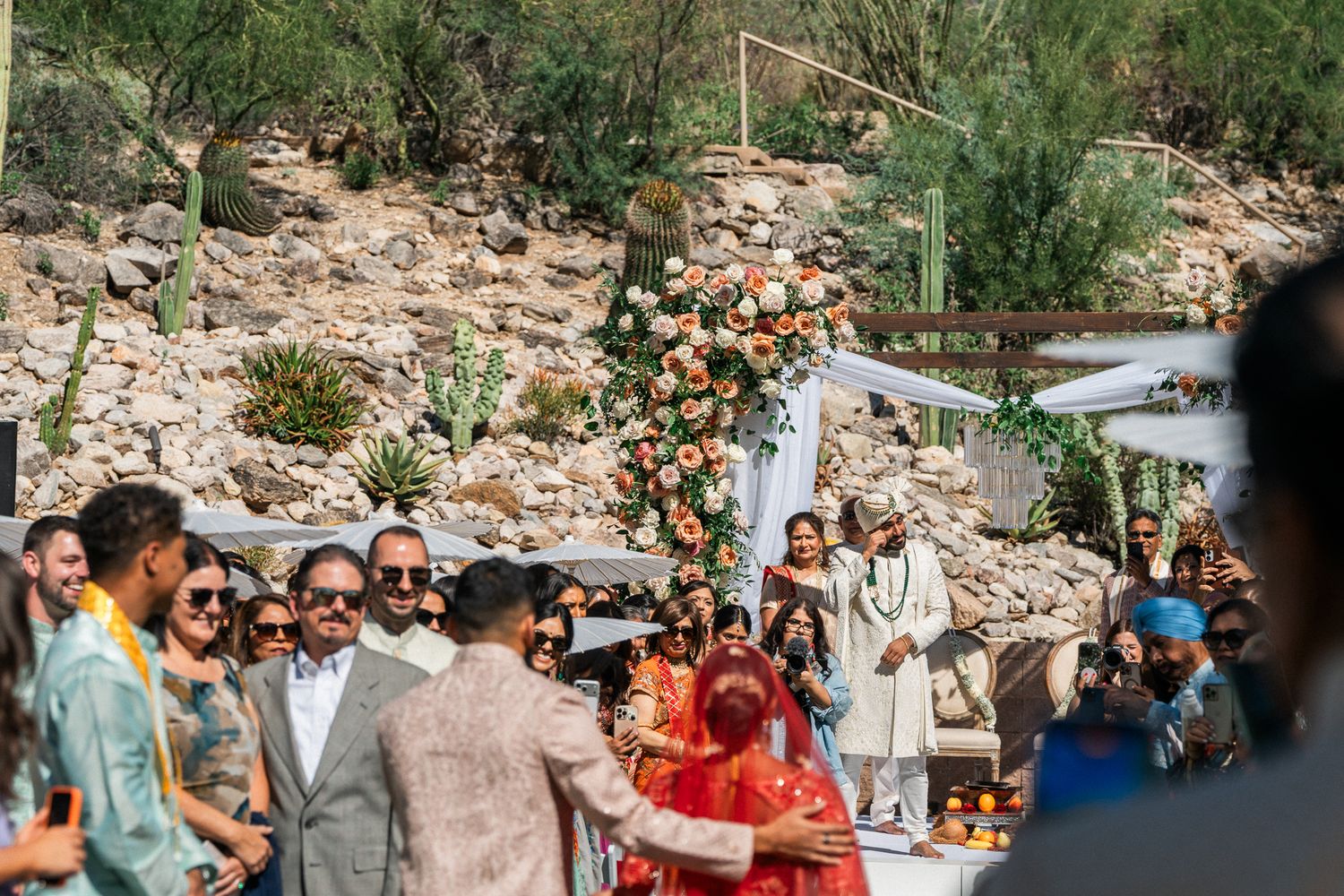 Outdoor wedding ceremony with guests seated among desert rock formations.