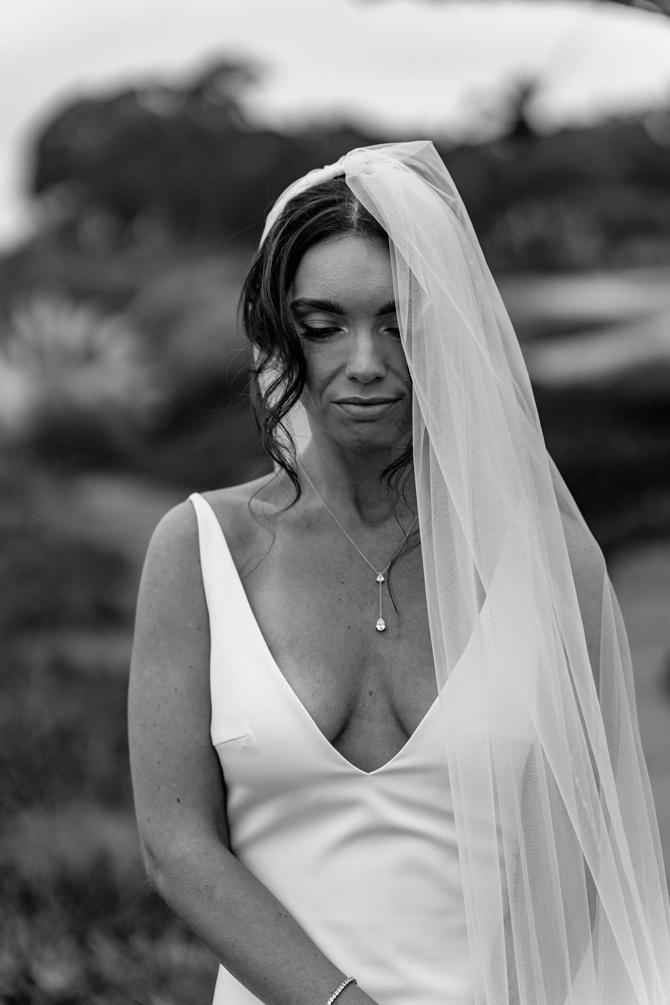 Intimate black and white bridal portrait with flowing veil and necklace.
