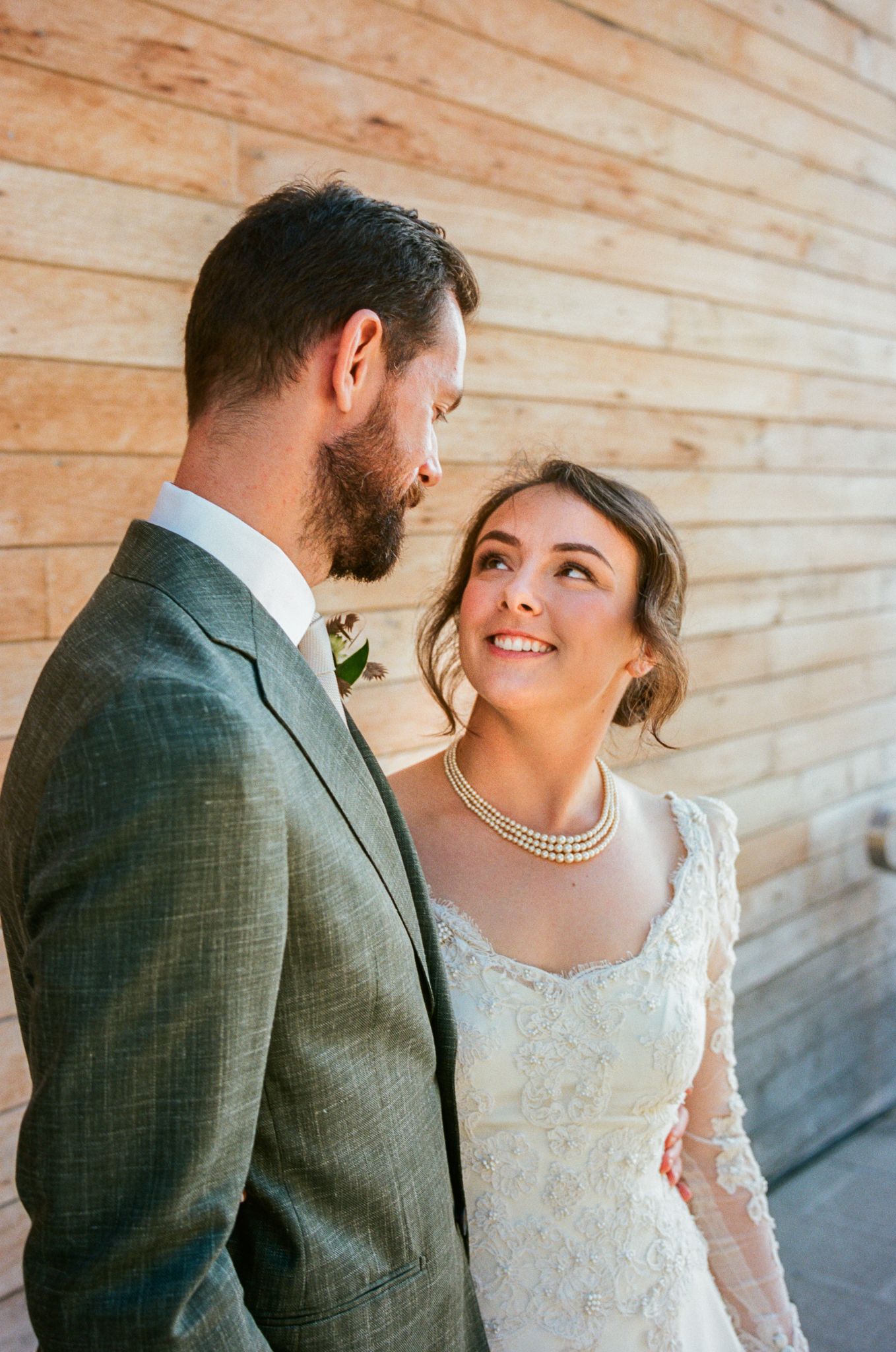 Close-up wedding portraits against weathered wood paneling.