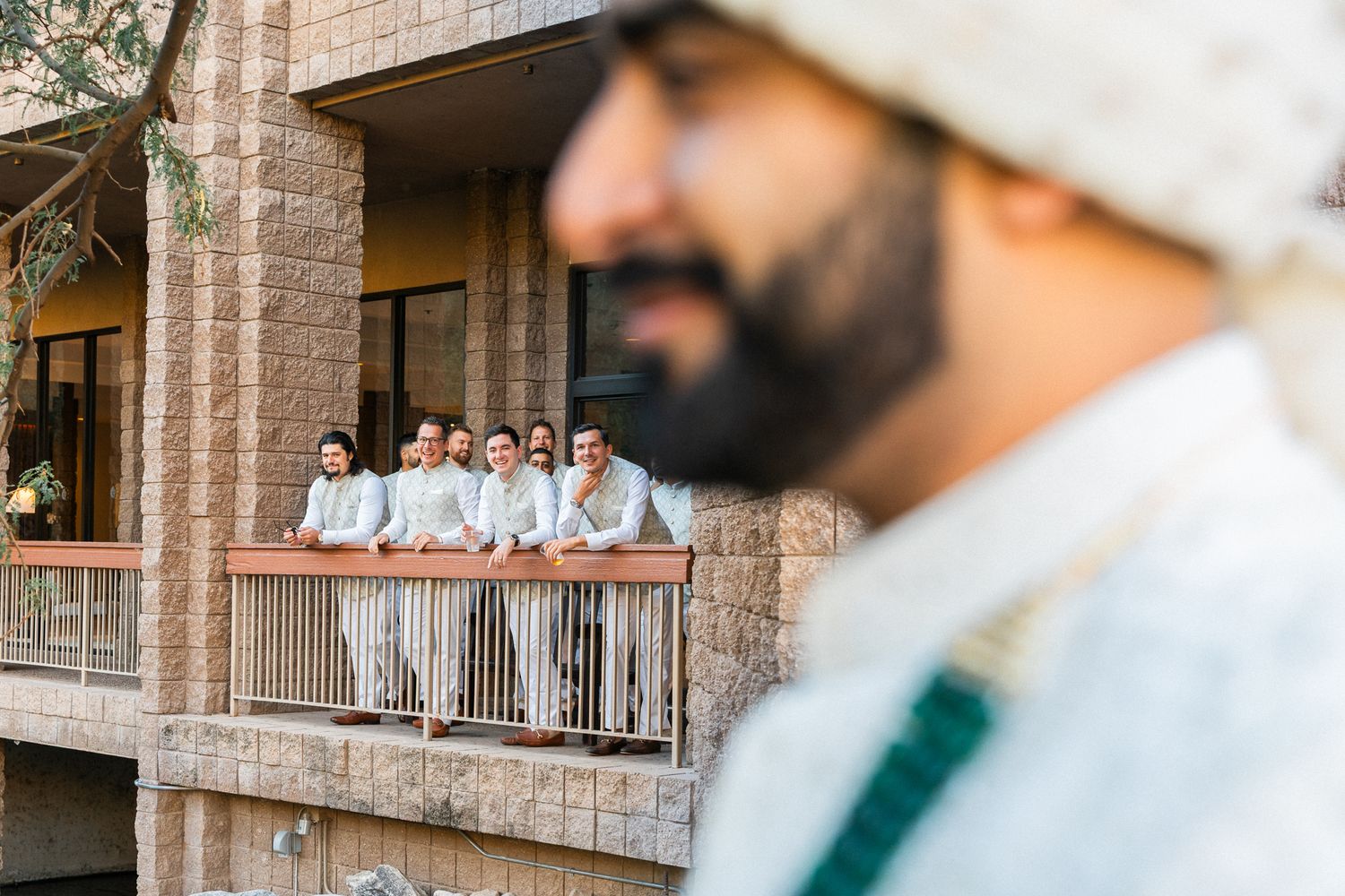 Wedding guests watch from a balcony during an outdoor celebration.