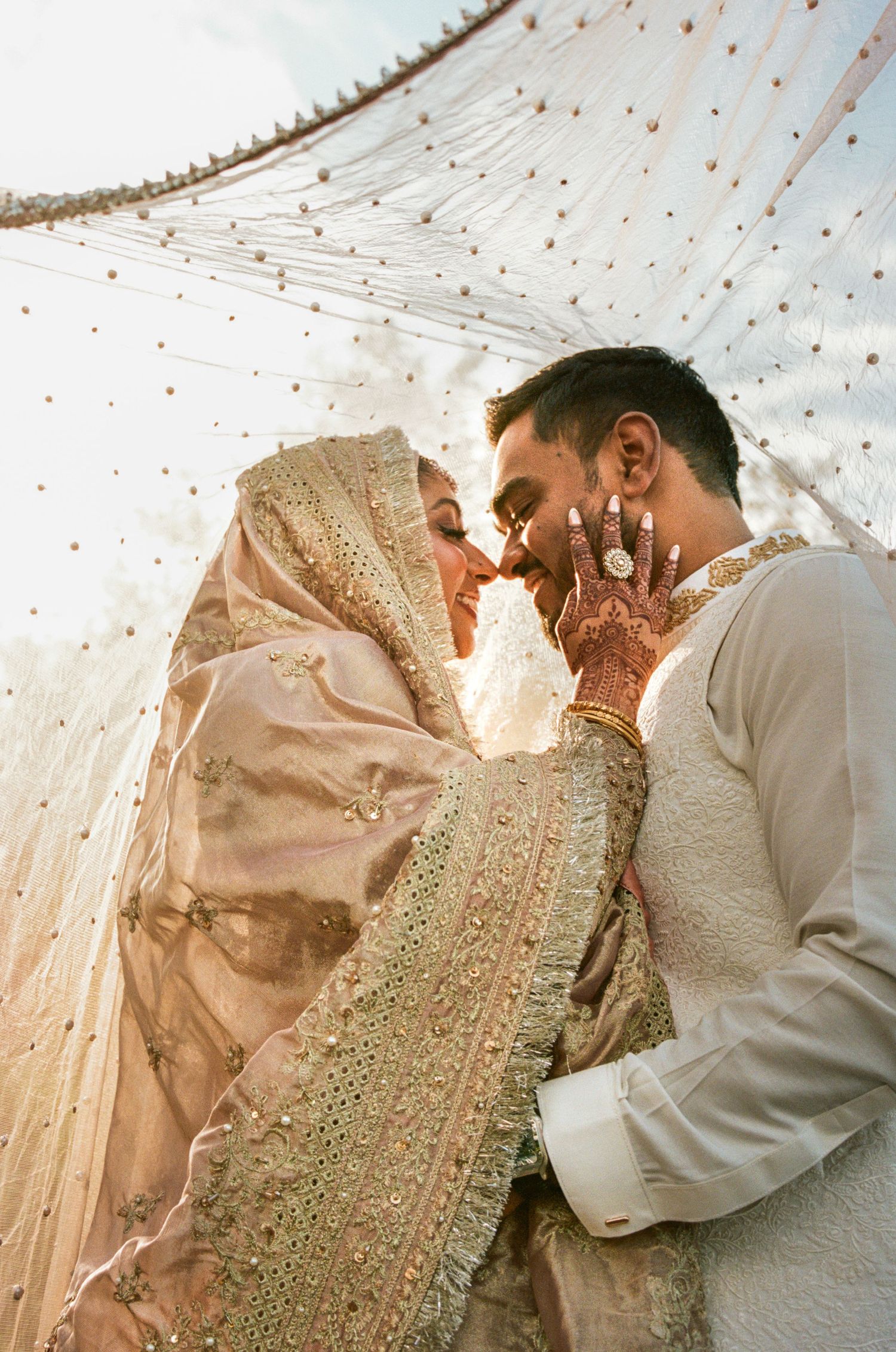 Intimate wedding moment captured under delicate string lights during golden hour.