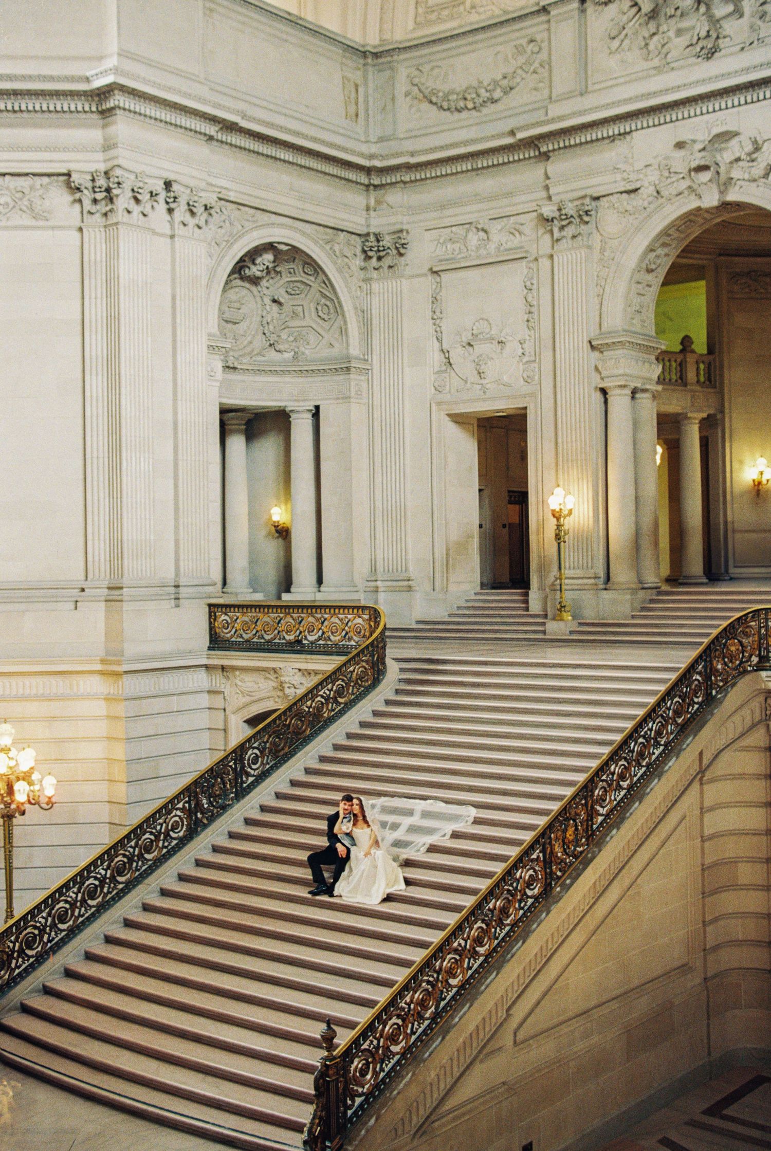 Bride and groom share a romantic embrace on the grand staircase of San Francisco City Hall.